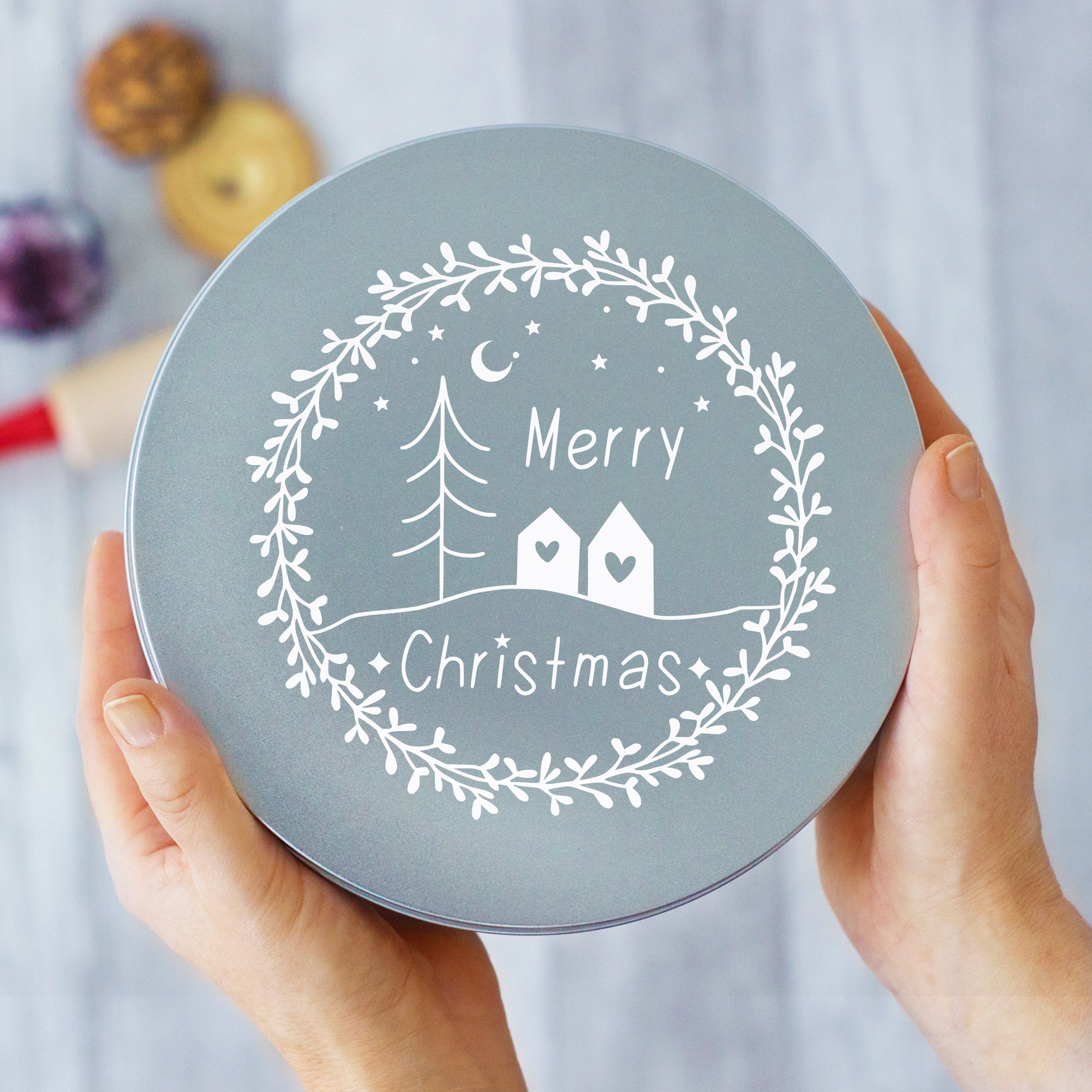 Graue Geschenkbox mit weißem Weihnachtsmotiv und Schriftzug.