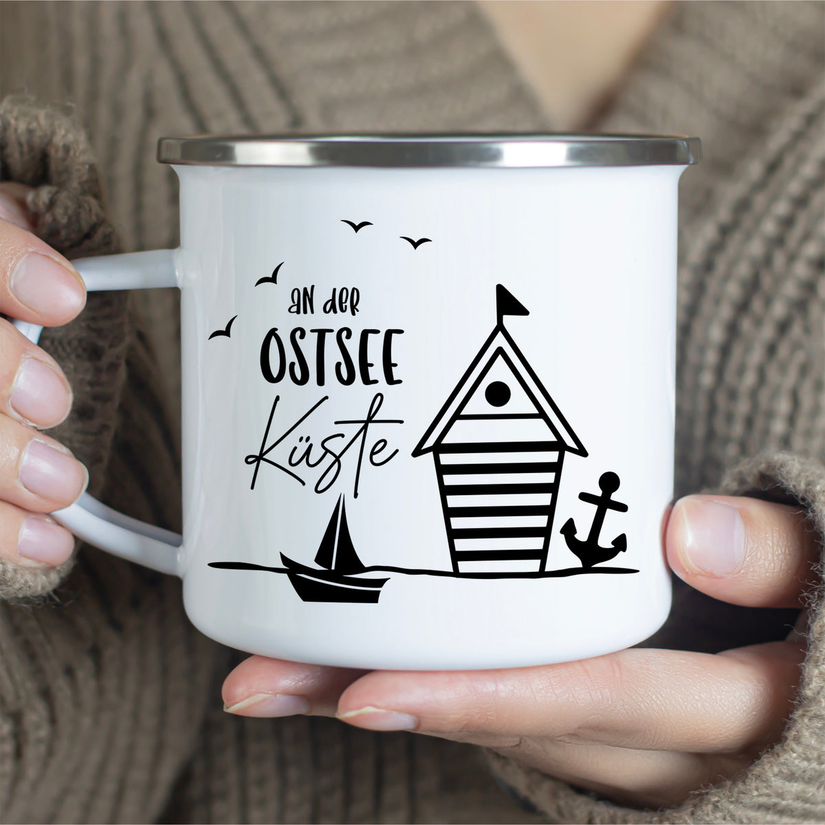 Weißer Emaillebecher mit Ostsee-Motiv und Anker.