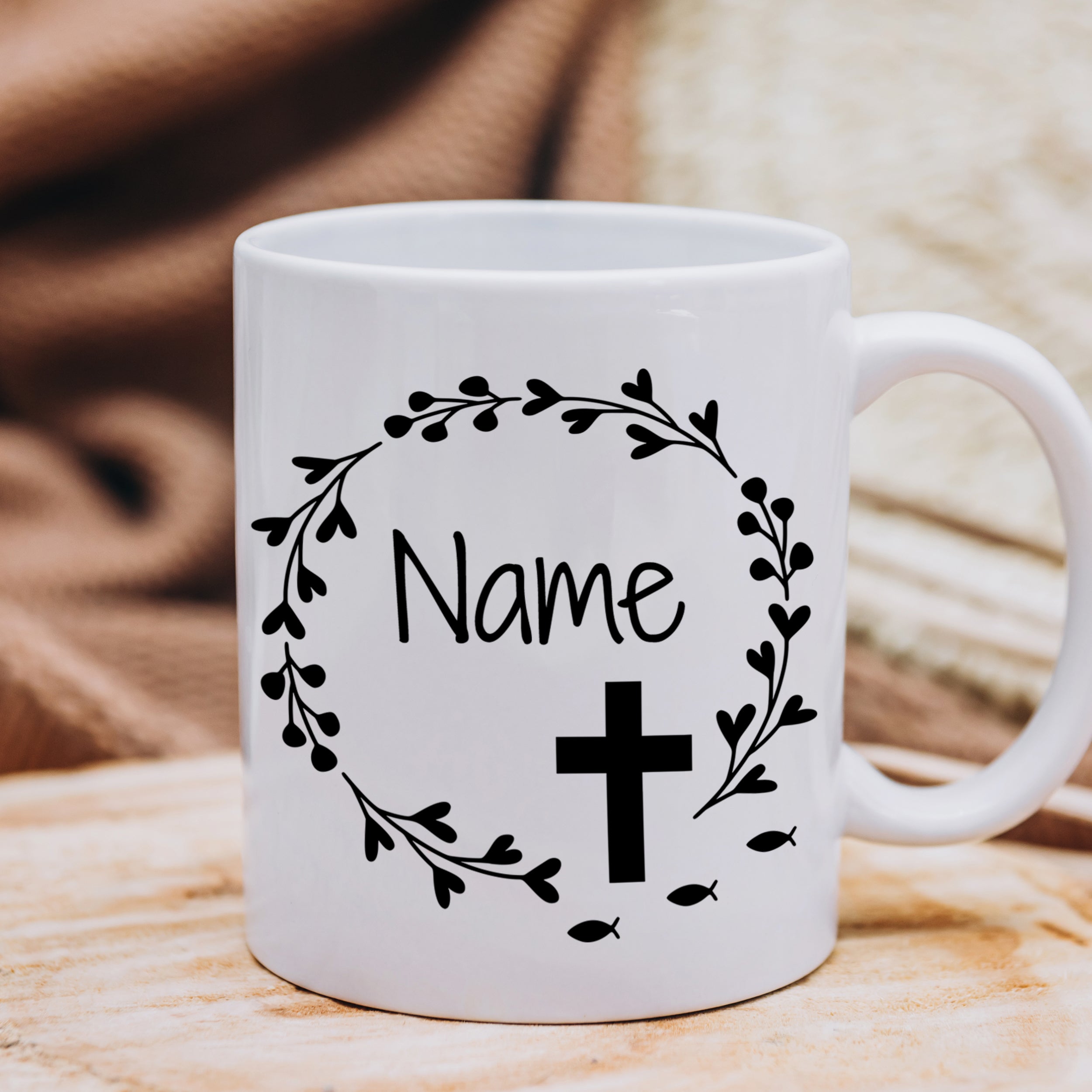 Weißer Becher mit schwarzem Kreuz und Pflanzenmotiv.