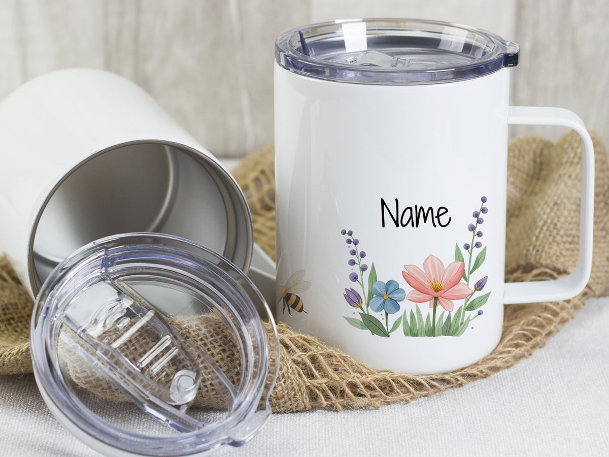 Weißer Becher mit bunten Blumen und personalisierbarem Namen.