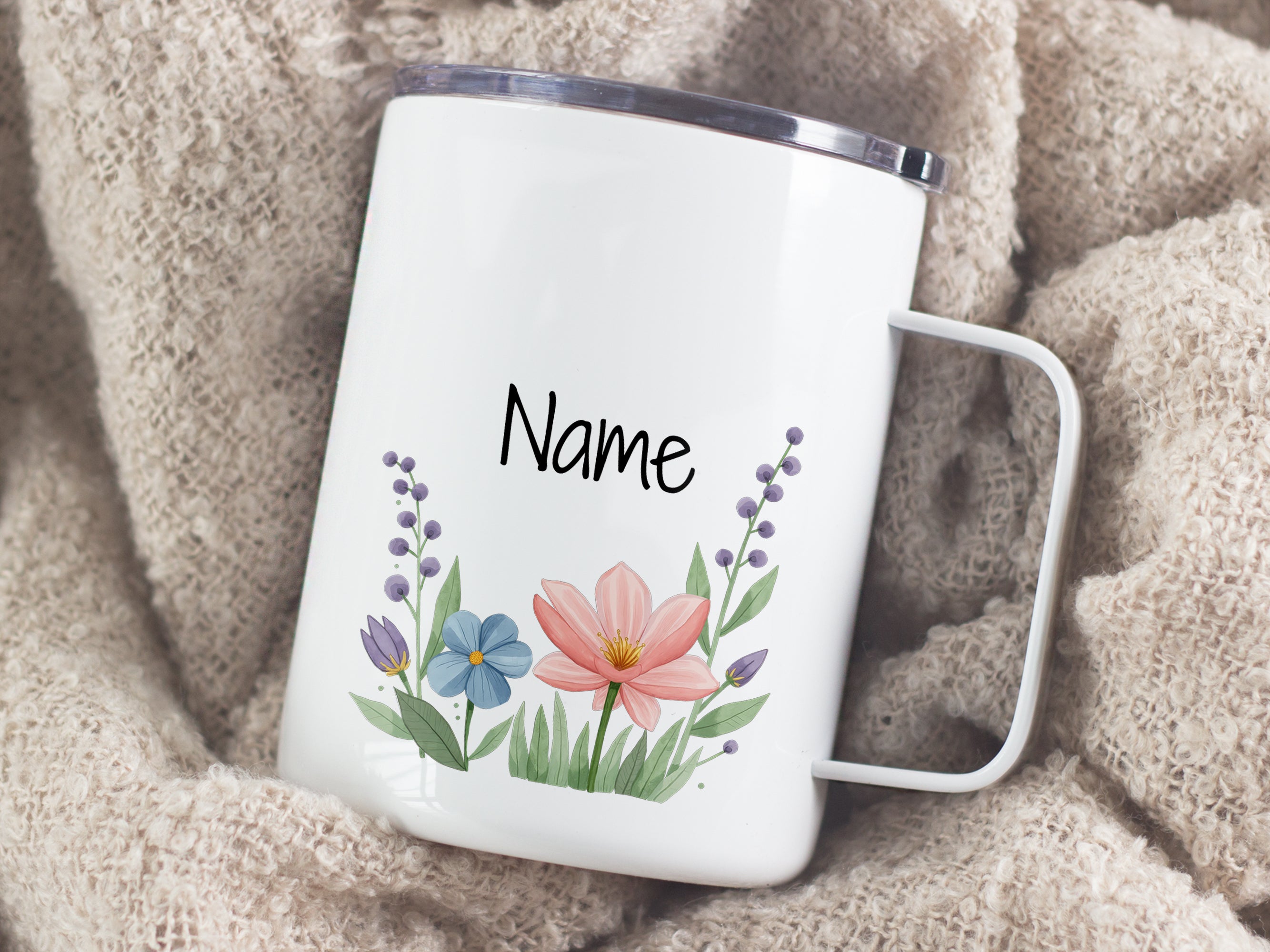 Weißer Becher mit bunten Blumen und personalisiertem Namen.