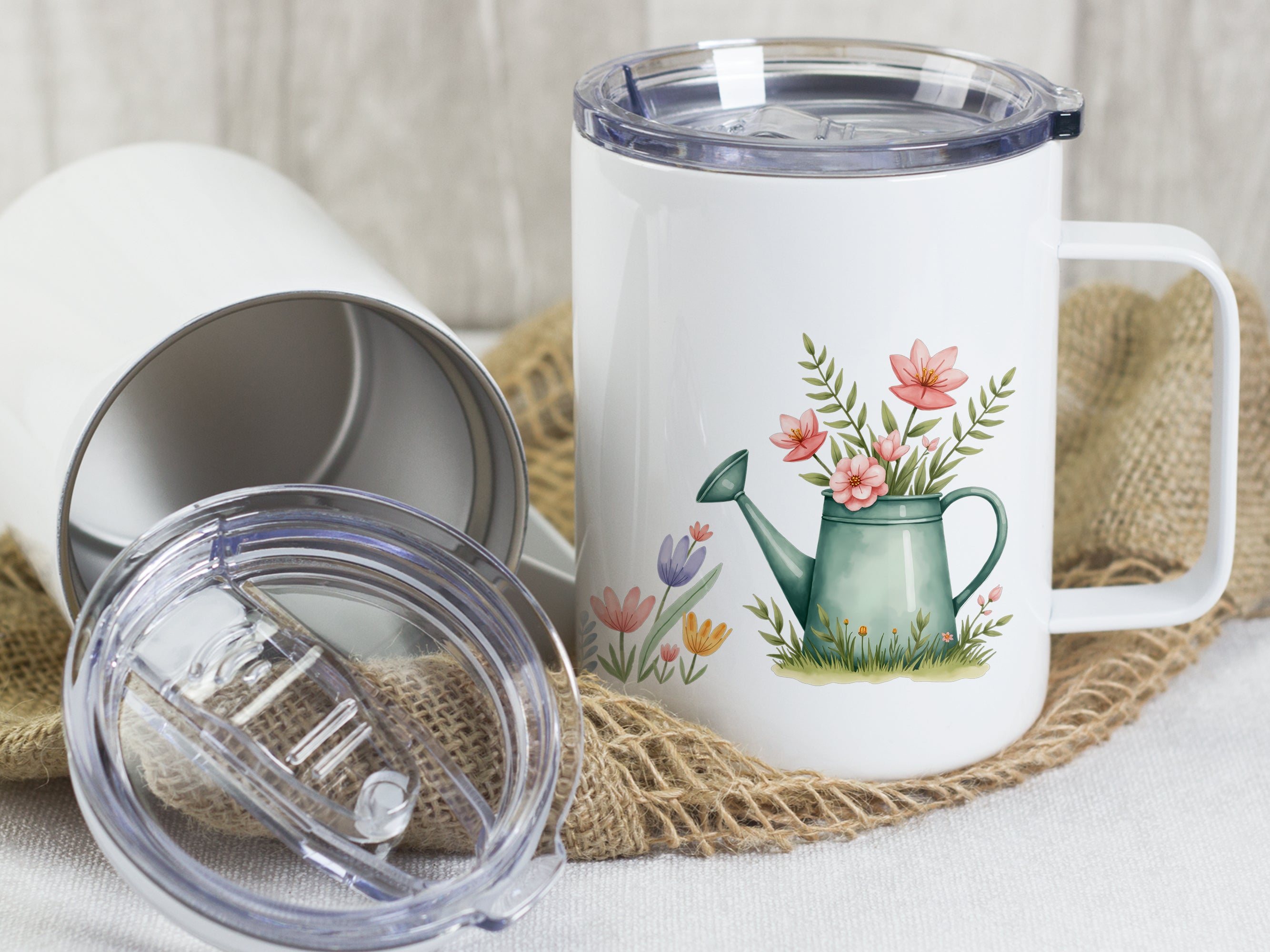 Weißer Becher mit Blumenmotiv und grüner Gießkanne.