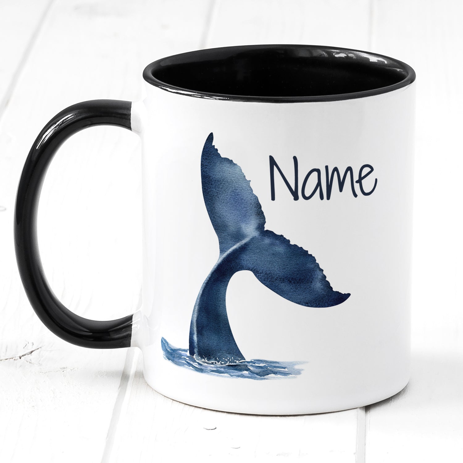 Tasse mit schwarzem Henkel, blauer Walfischflosse und Name.