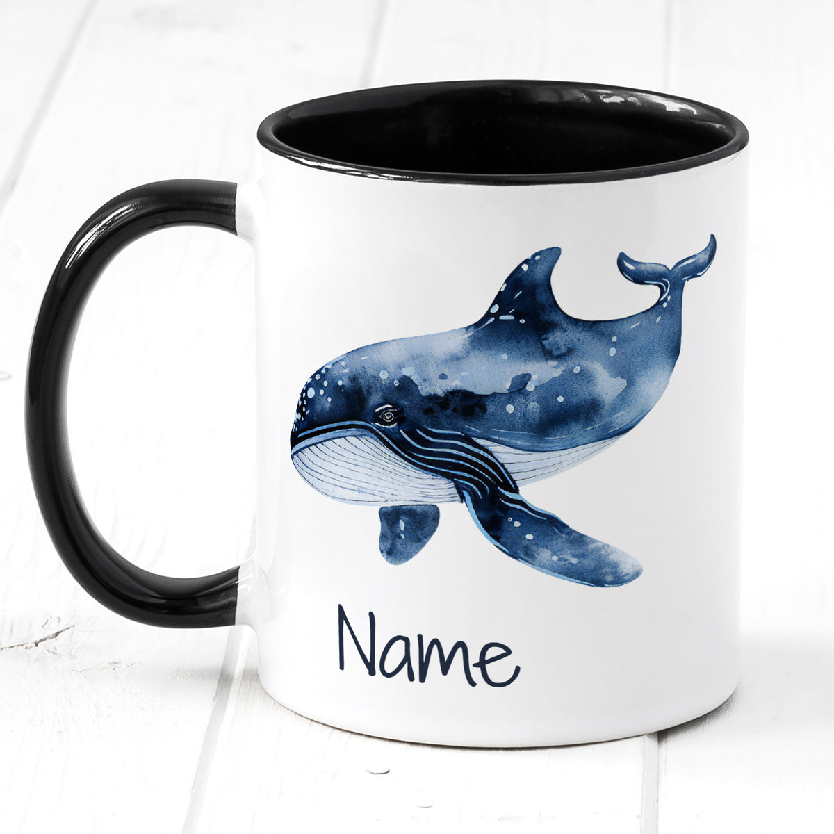 Tasse mit blauer Wal-Illustration und schwarzem Henkel.