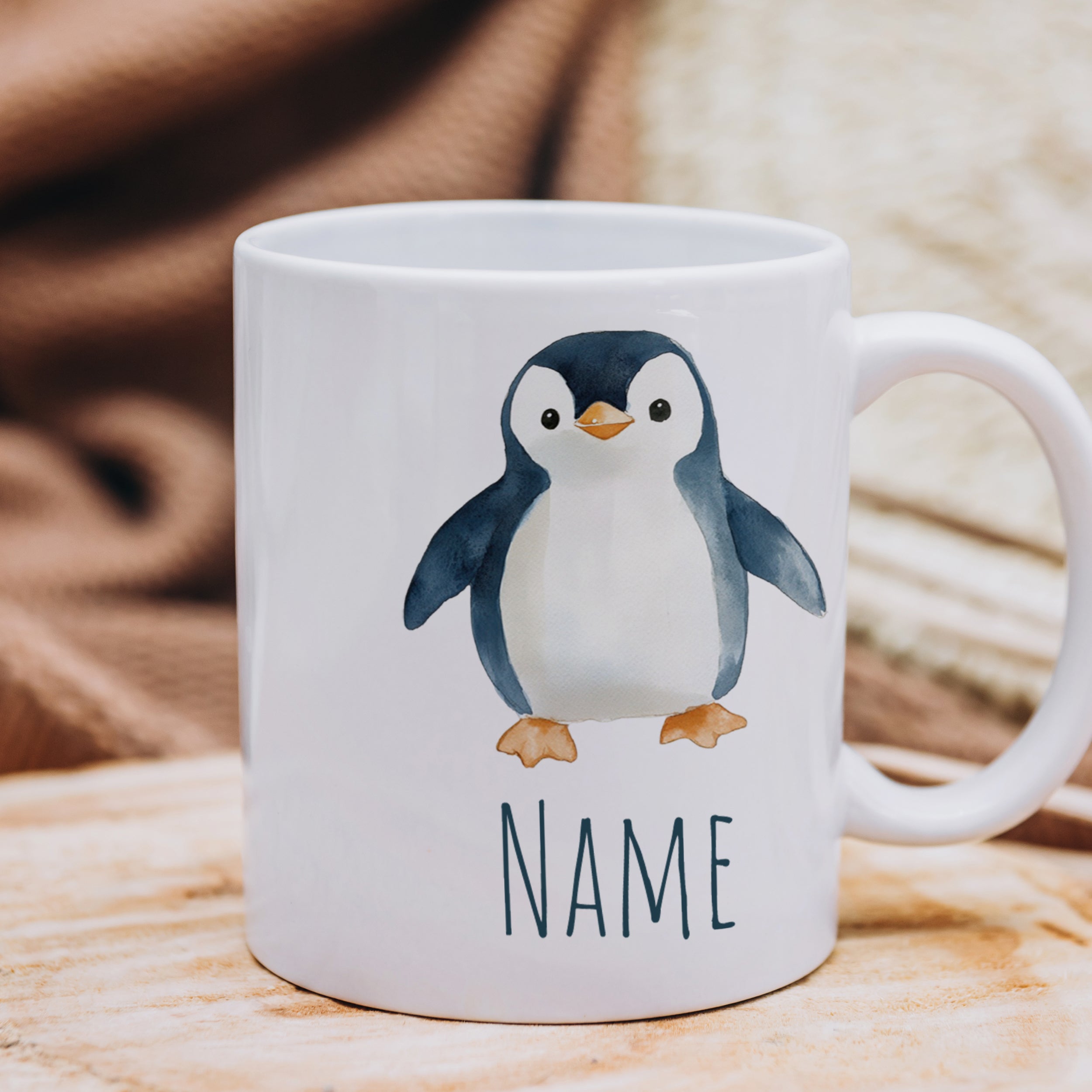 Weißer Becher mit Pinguin-Motiv und personalisierbarem Namen.