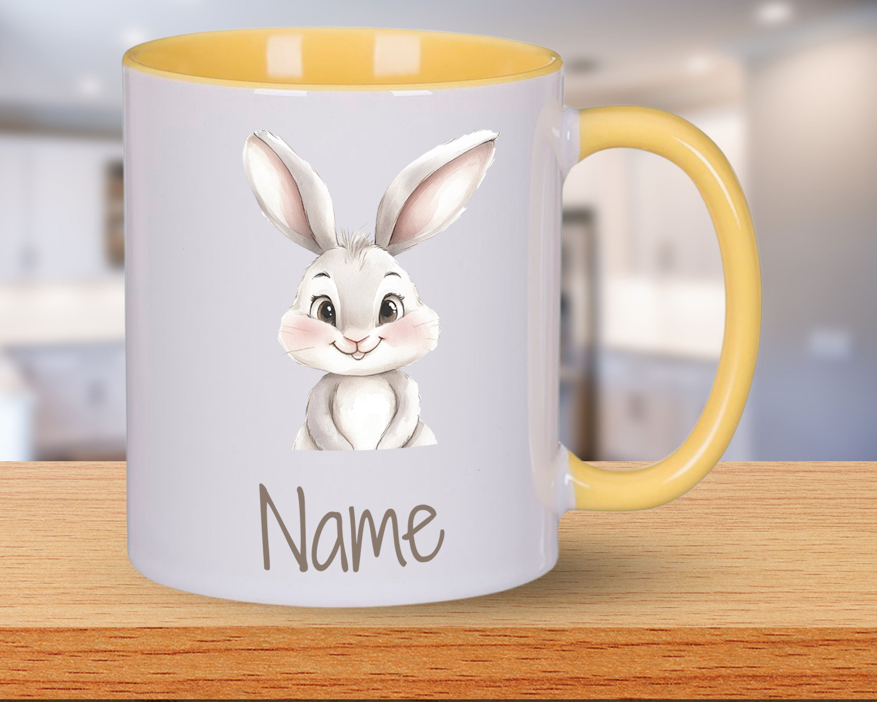 Tasse mit gelbem Henkel und niedlichem Hasenmotiv.