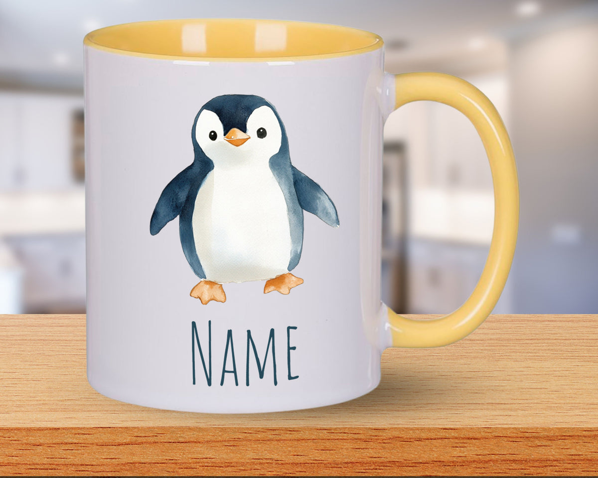Tasse mit Pinguin-Motiv und gelbem Henkel.