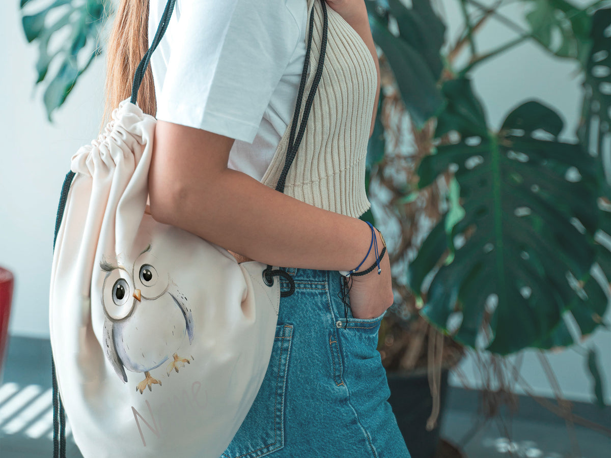 Beige Rucksack mit Eulenmotiv, lässig getragen.