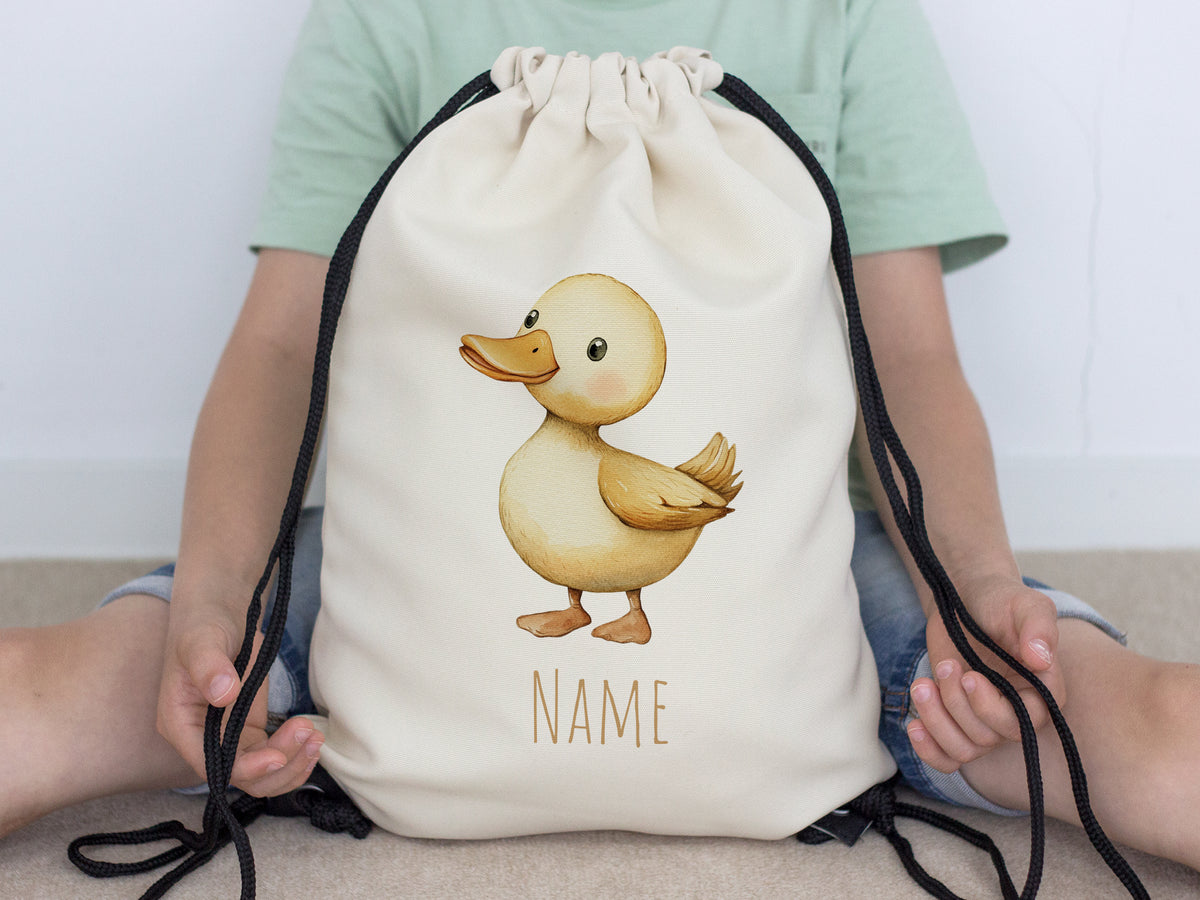 Beige Turnbeutel mit Entenmotiv und Platz für Namen.