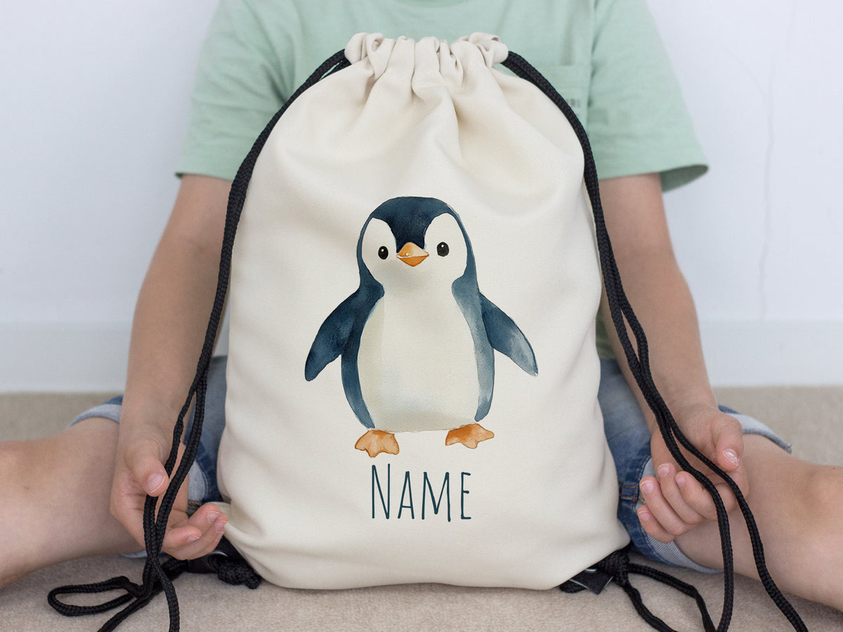 Beige Turnbeutel mit Pinguin-Motiv und Platz für Namen.