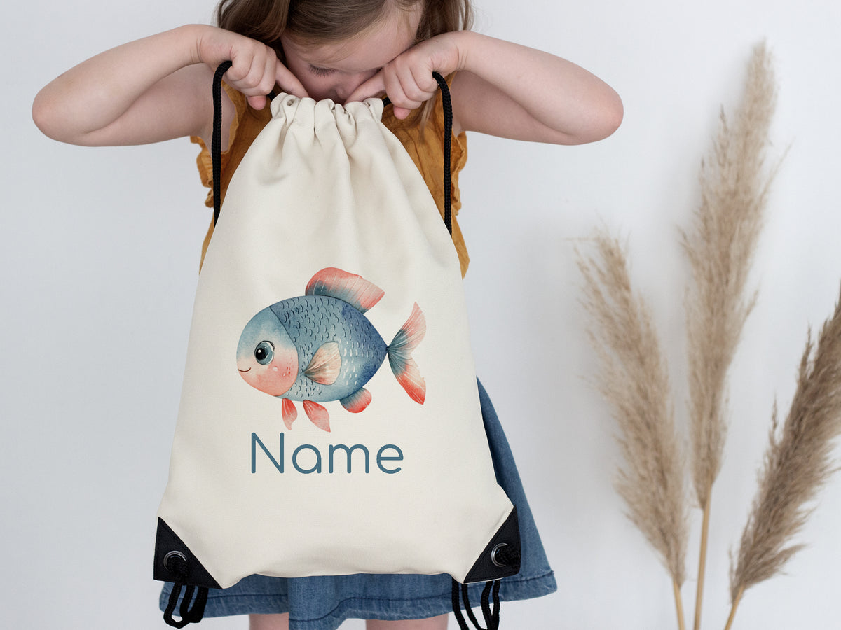 Beige Turnbeutel mit buntem Fisch und personalisierbarem Namen.