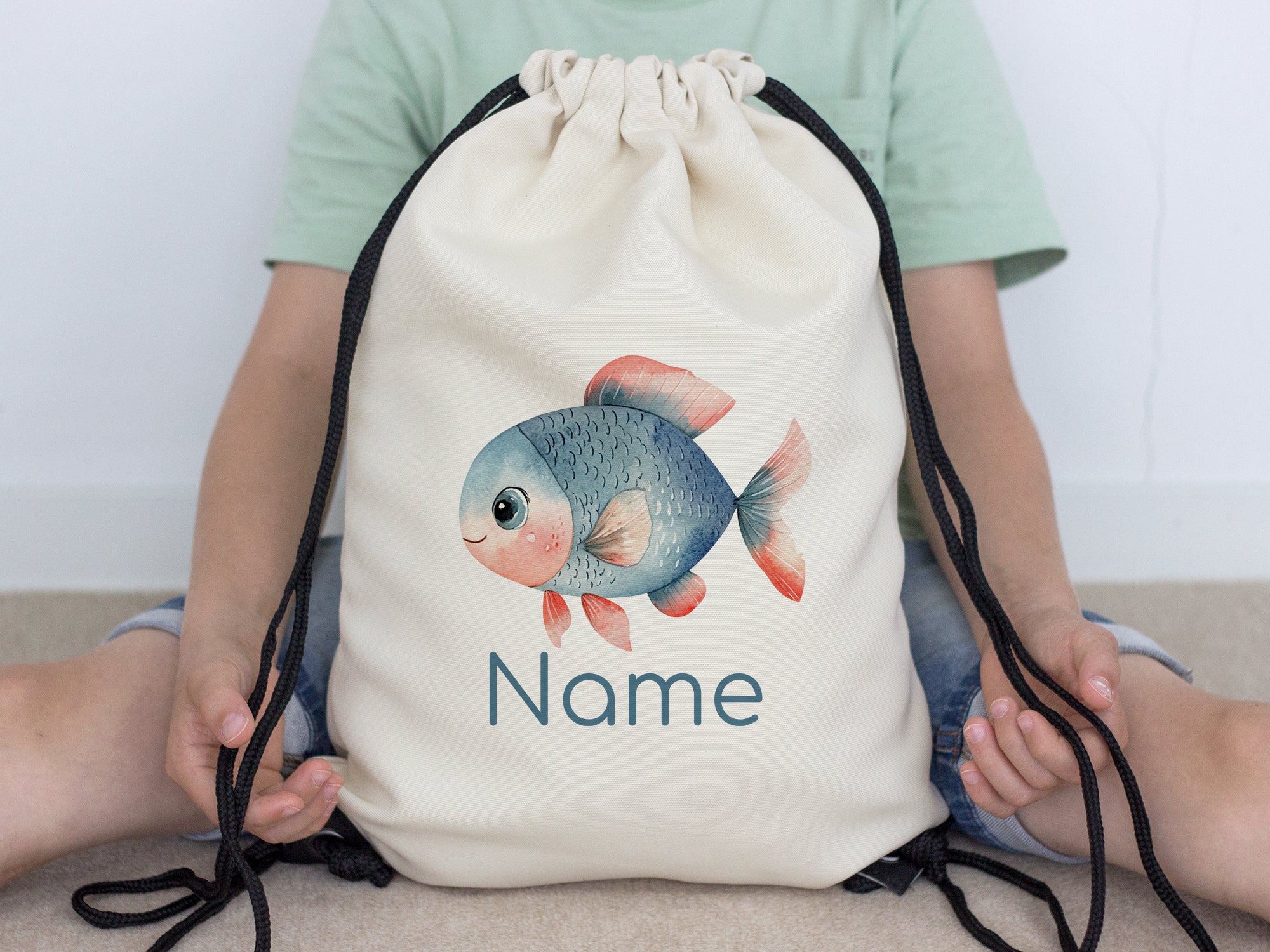 Beige Turnbeutel mit Fischmotiv und personalisierbarem Namen.