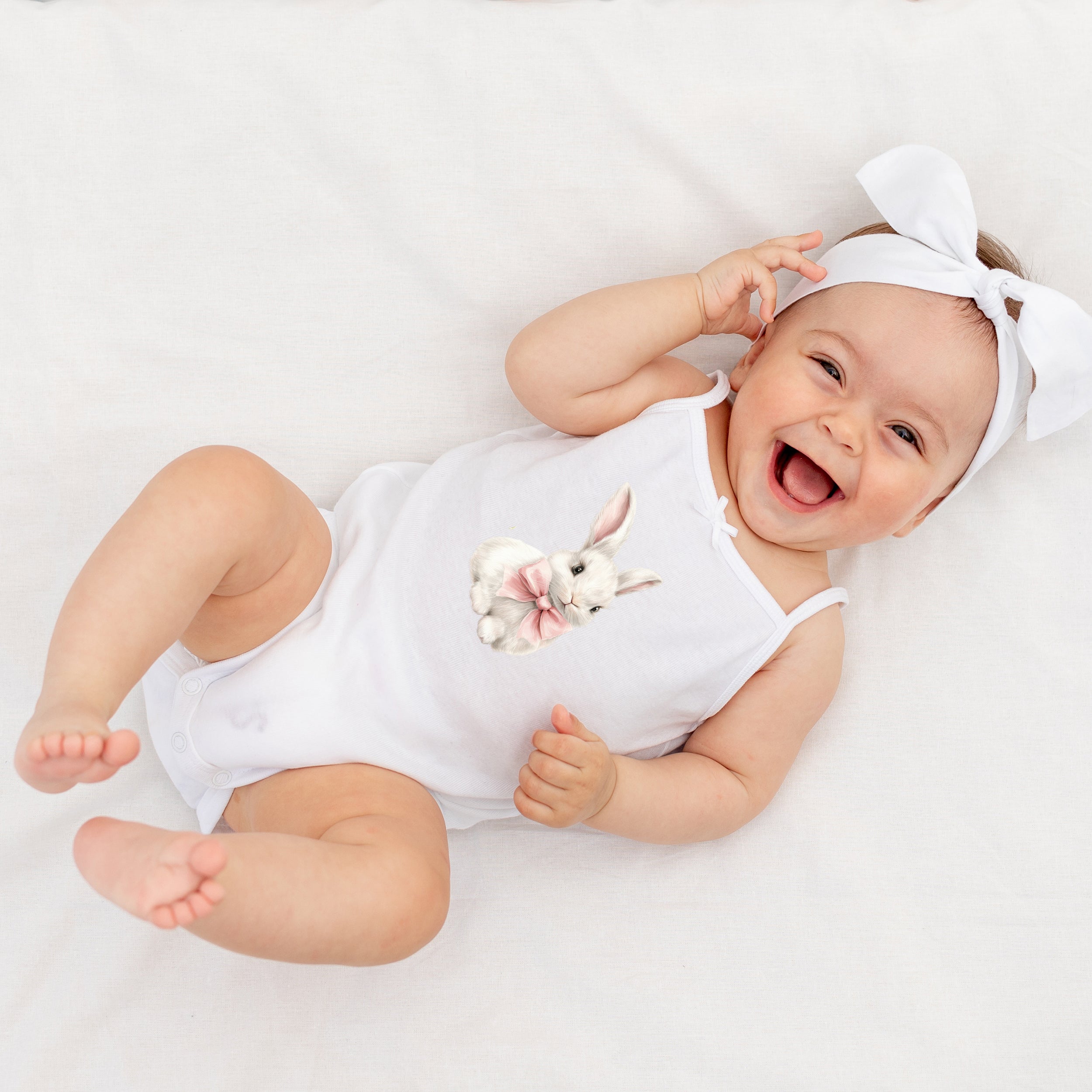 Weißer Baby-Body mit Hasenmotiv und Haarband.