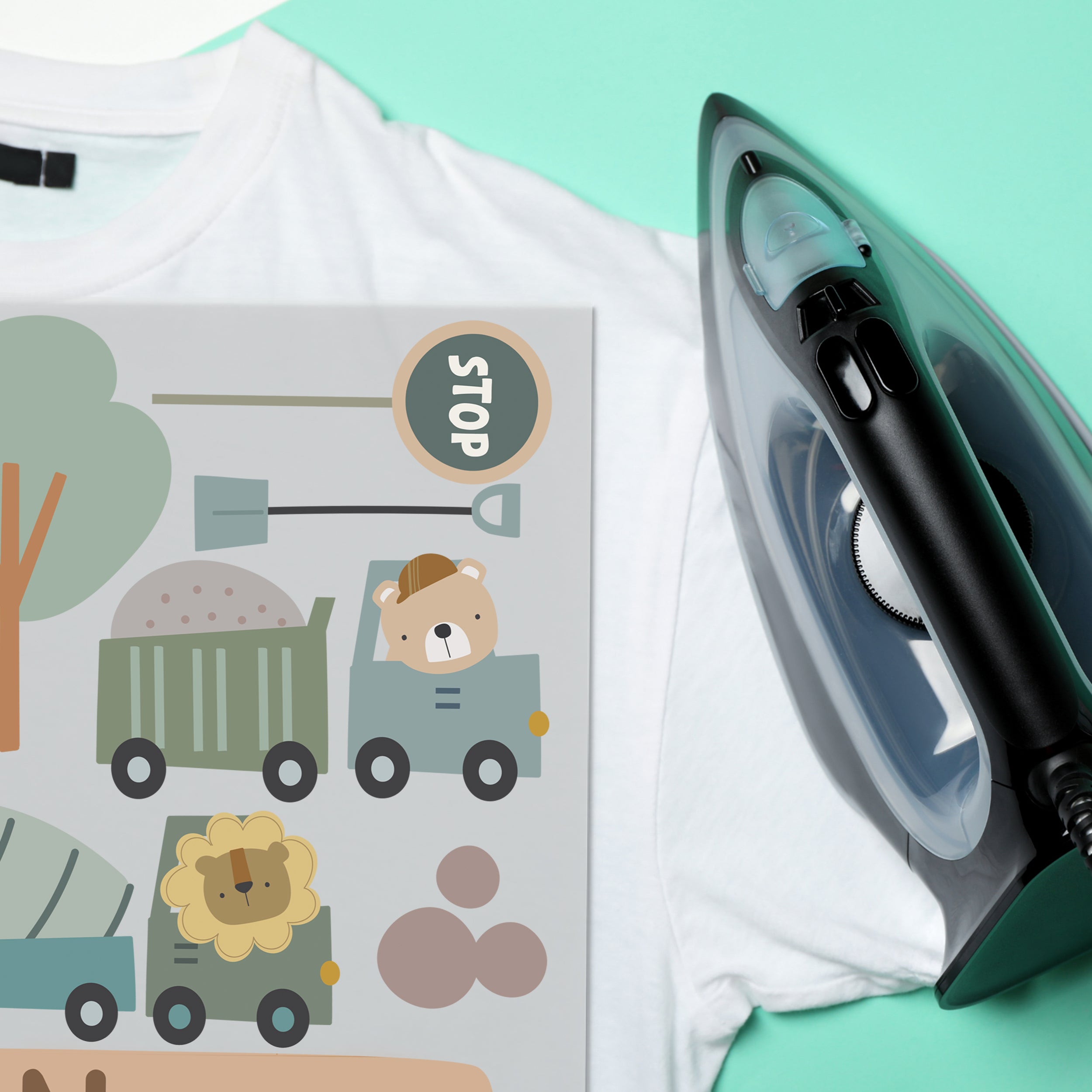 Bügeleisen neben T-Shirt mit bunten Tiermotiven.