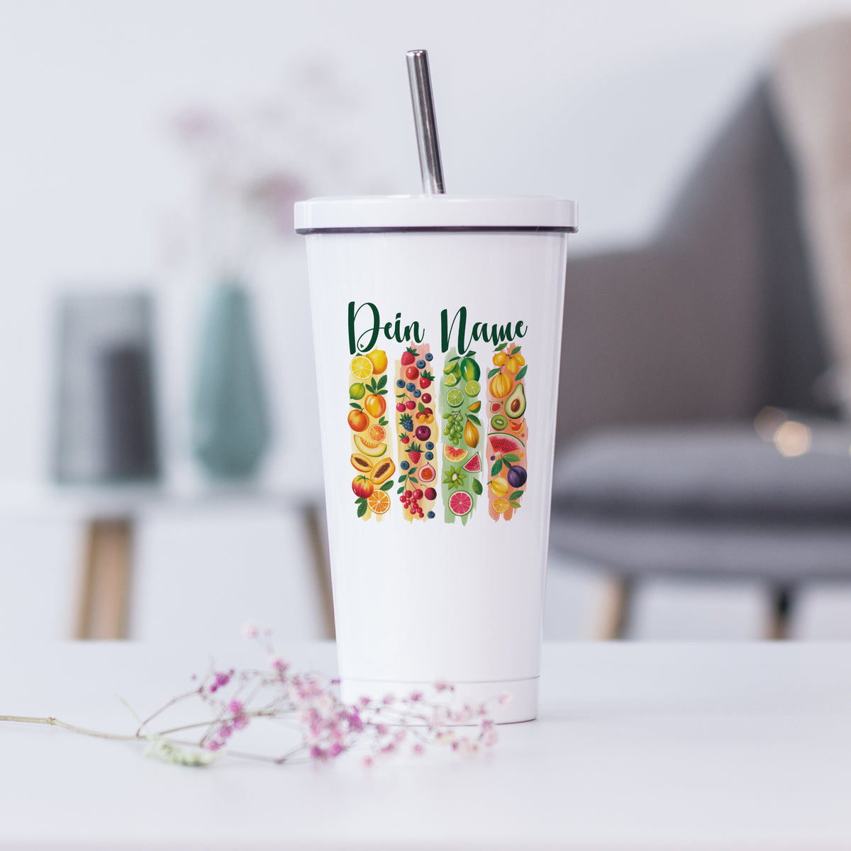 Weißer Becher mit bunten Obstmotiven und personalisiertem Namen.