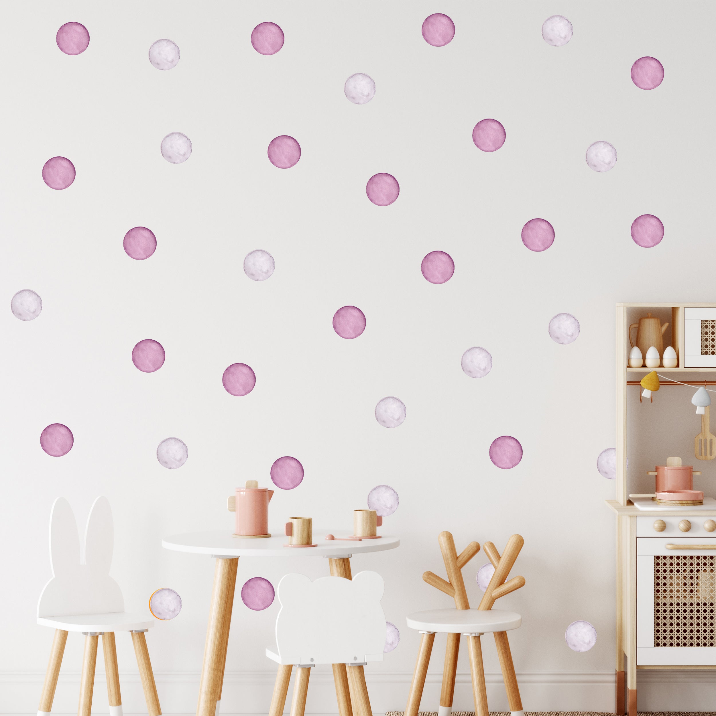 Rosa und lilafarbene Punkte auf weißer Wand.