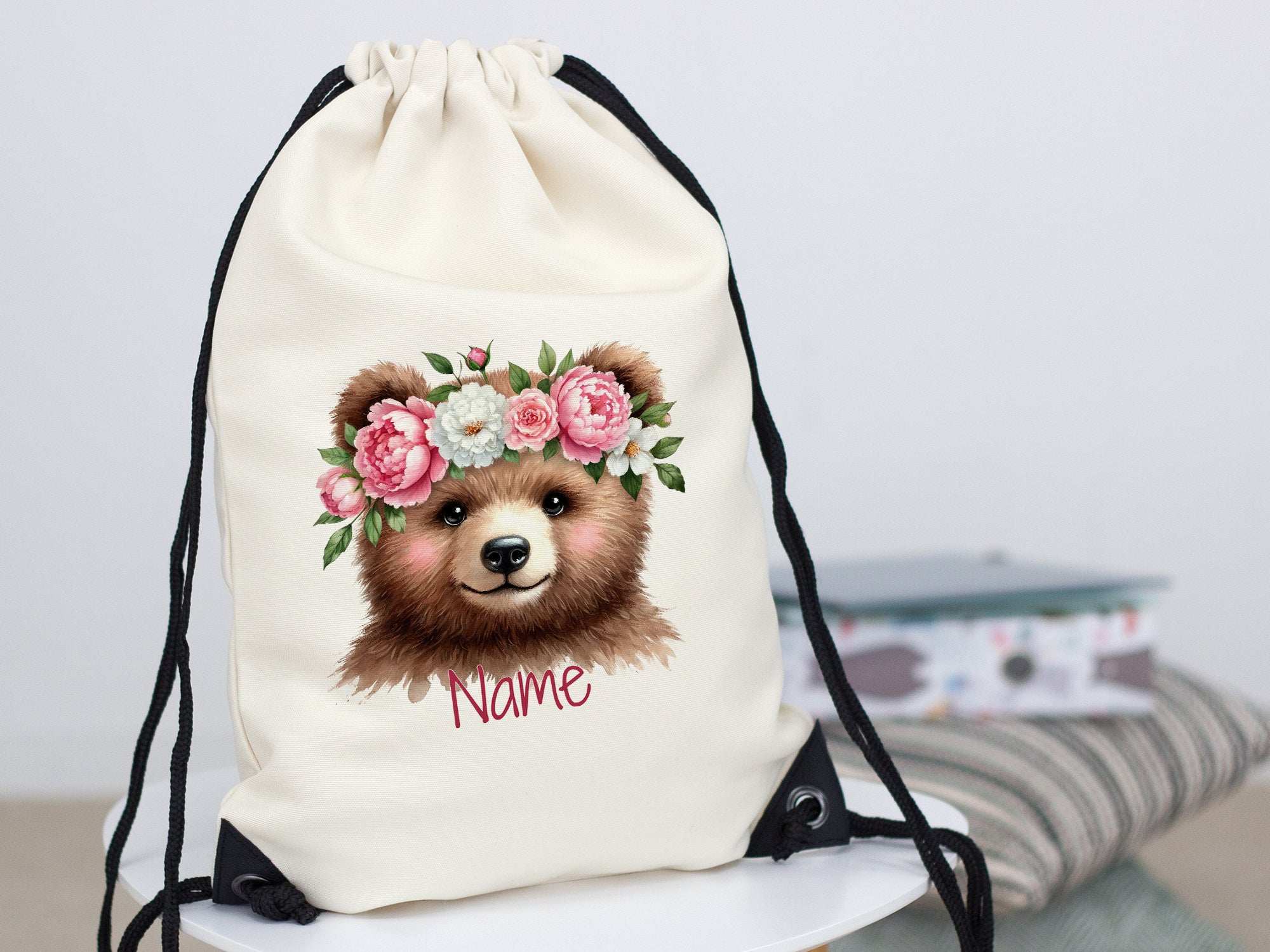 Beige Turnbeutel mit Bärenmotiv und Blumenkranz.
