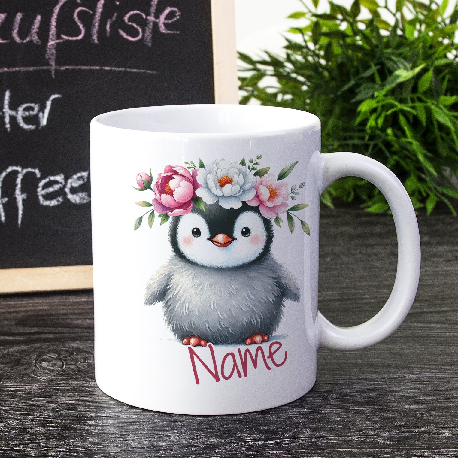 Tasse mit Pinguin, Blumenkranz und personalisiertem Namen.
