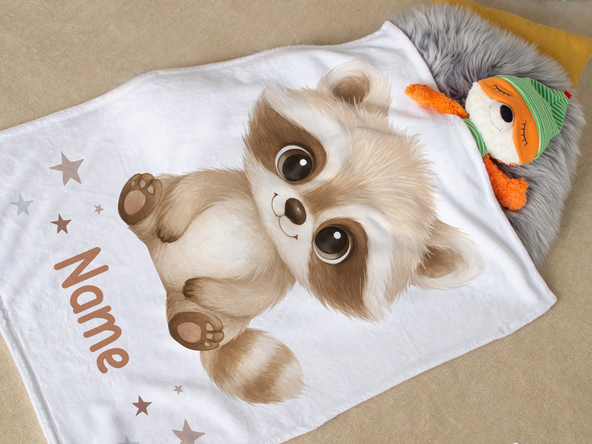 Weißes Kinderdecke mit niedlichem Waschbären-Motiv und personalisiertem Namen.