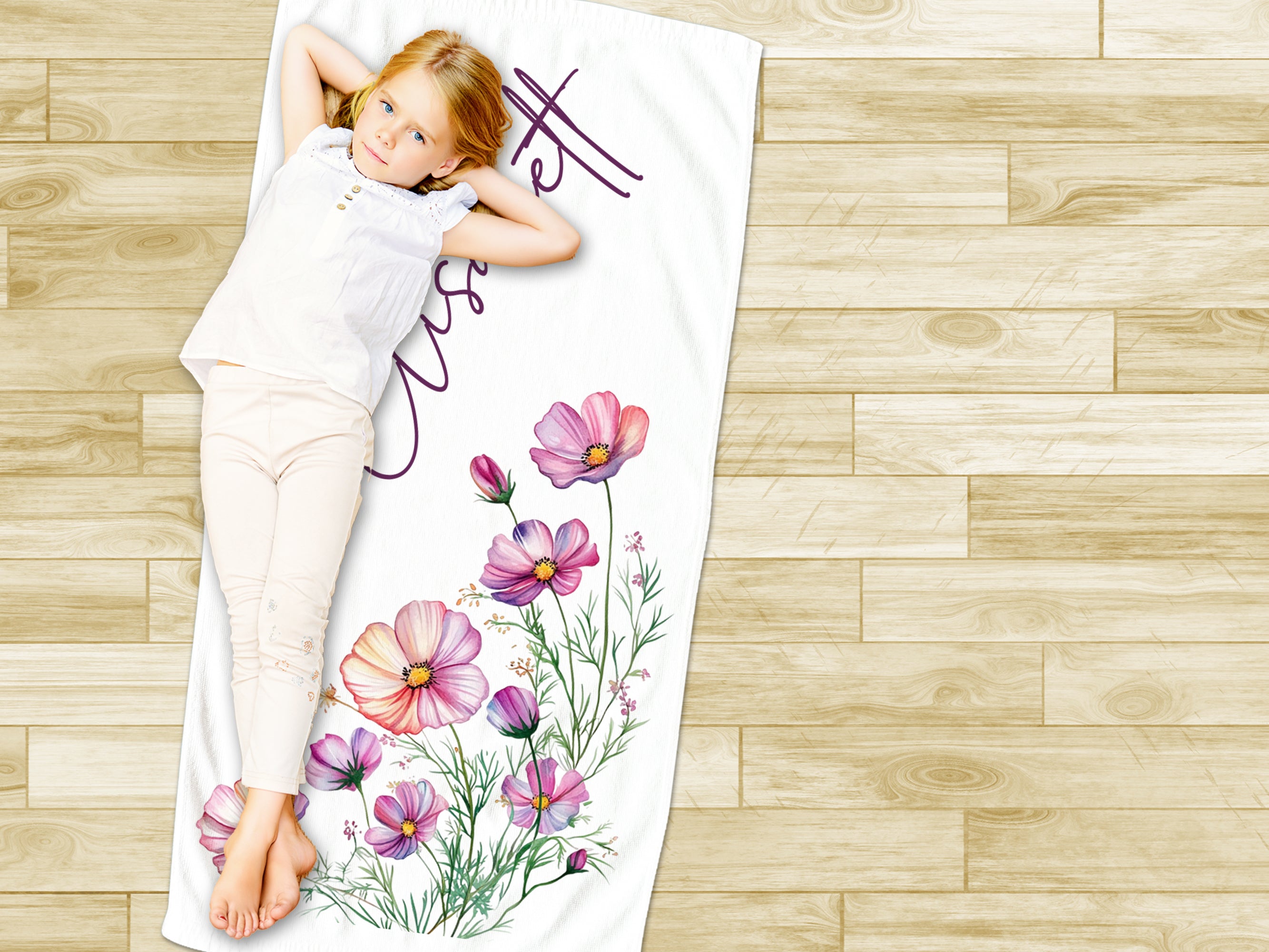 Mädchen auf Handtuch mit bunten Blumenmotiven.