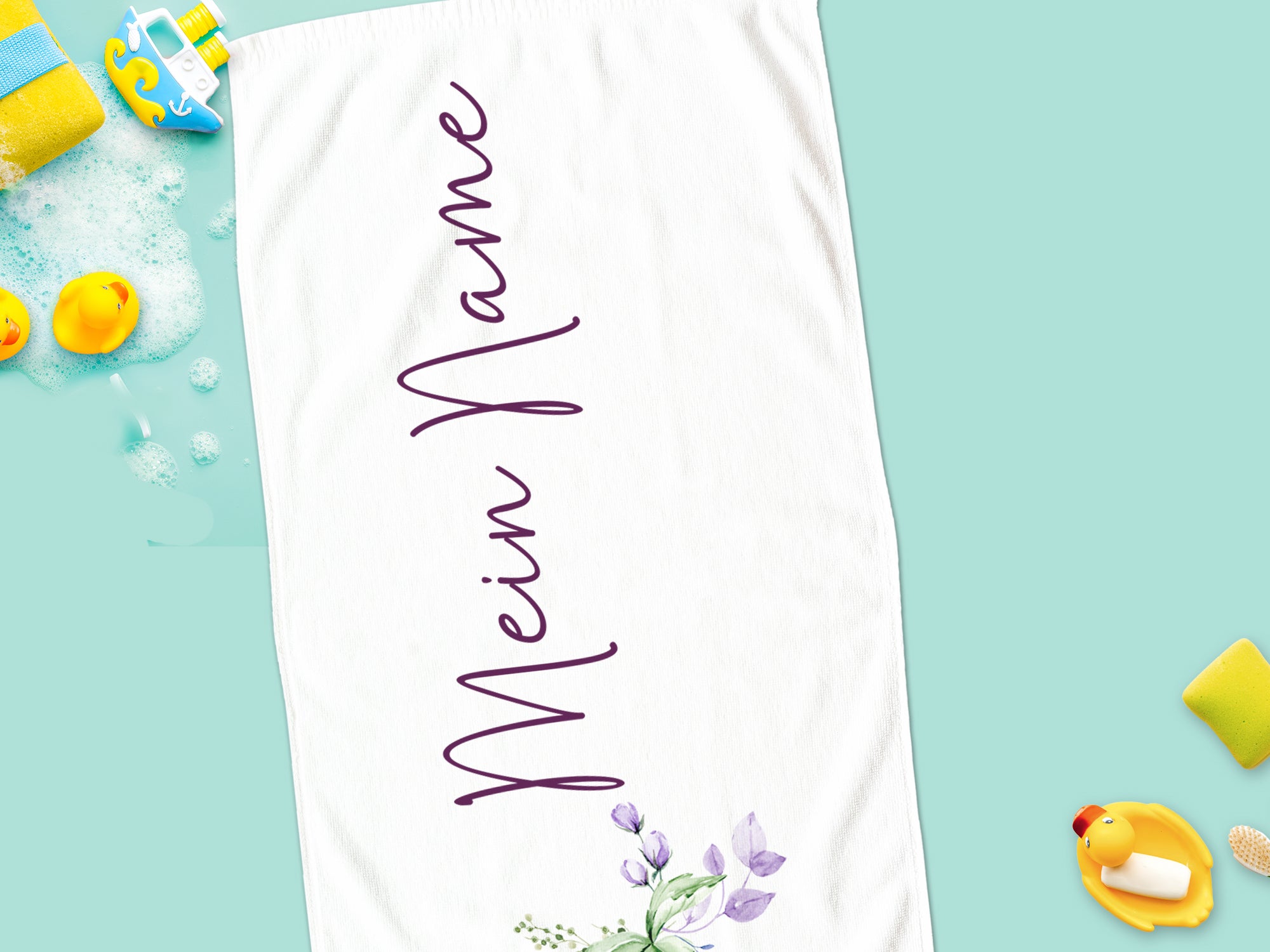 Weißes Handtuch mit lila Schriftzug und Blumenmotiv.