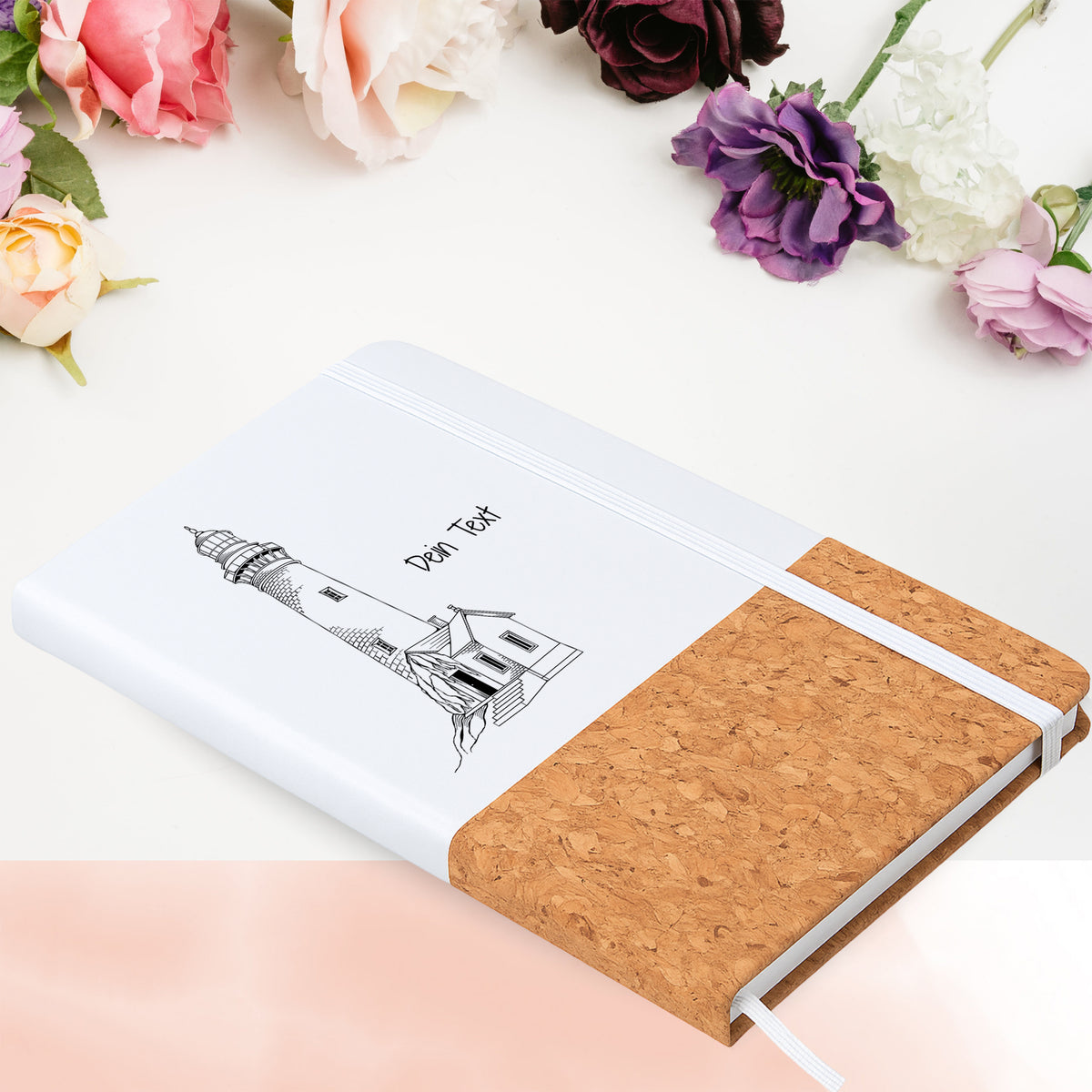 Notizbuch mit Leuchtturm auf Felsen in Blumenarrangement
