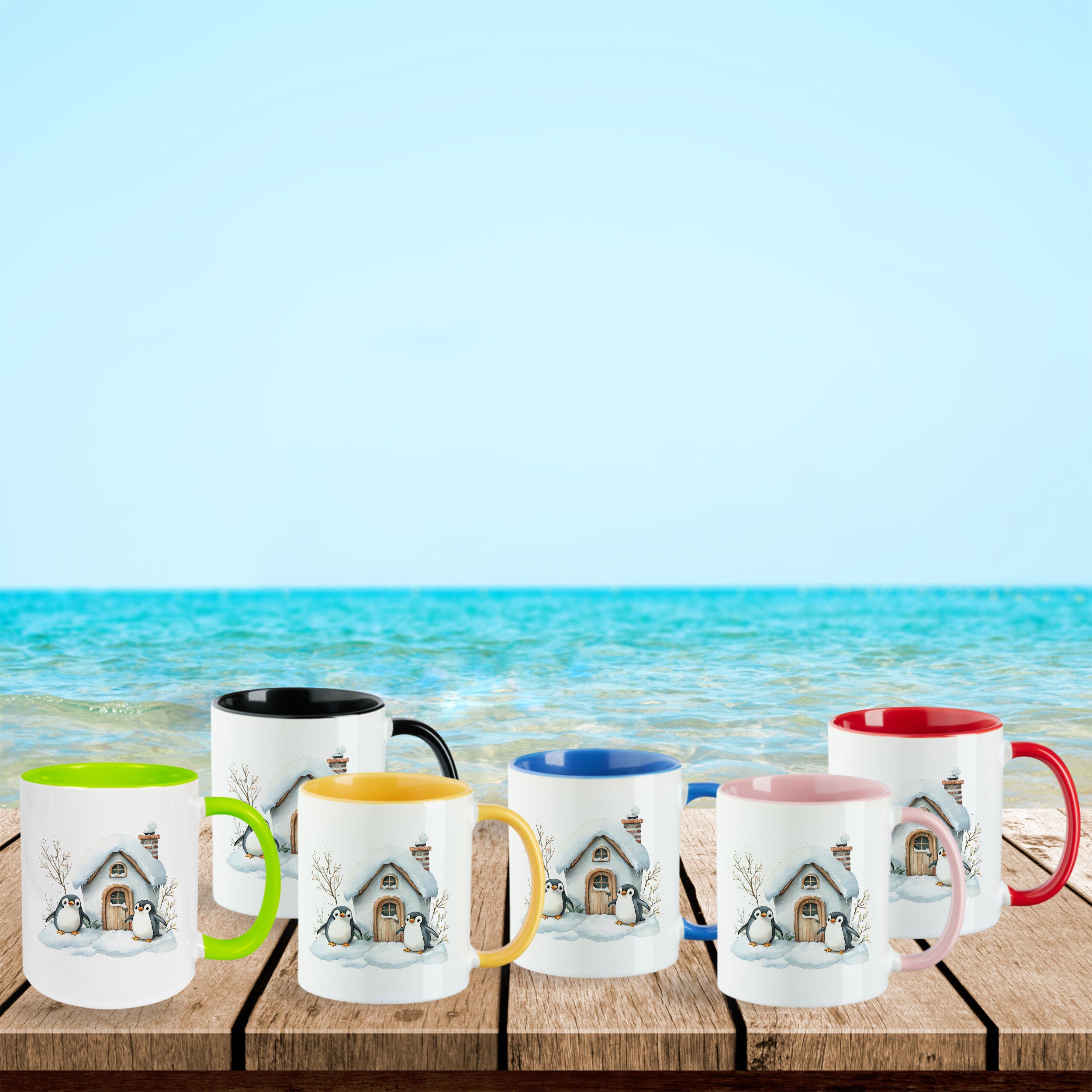 Bunte Tassen mit winterlichem Hausmotiv am Strand.