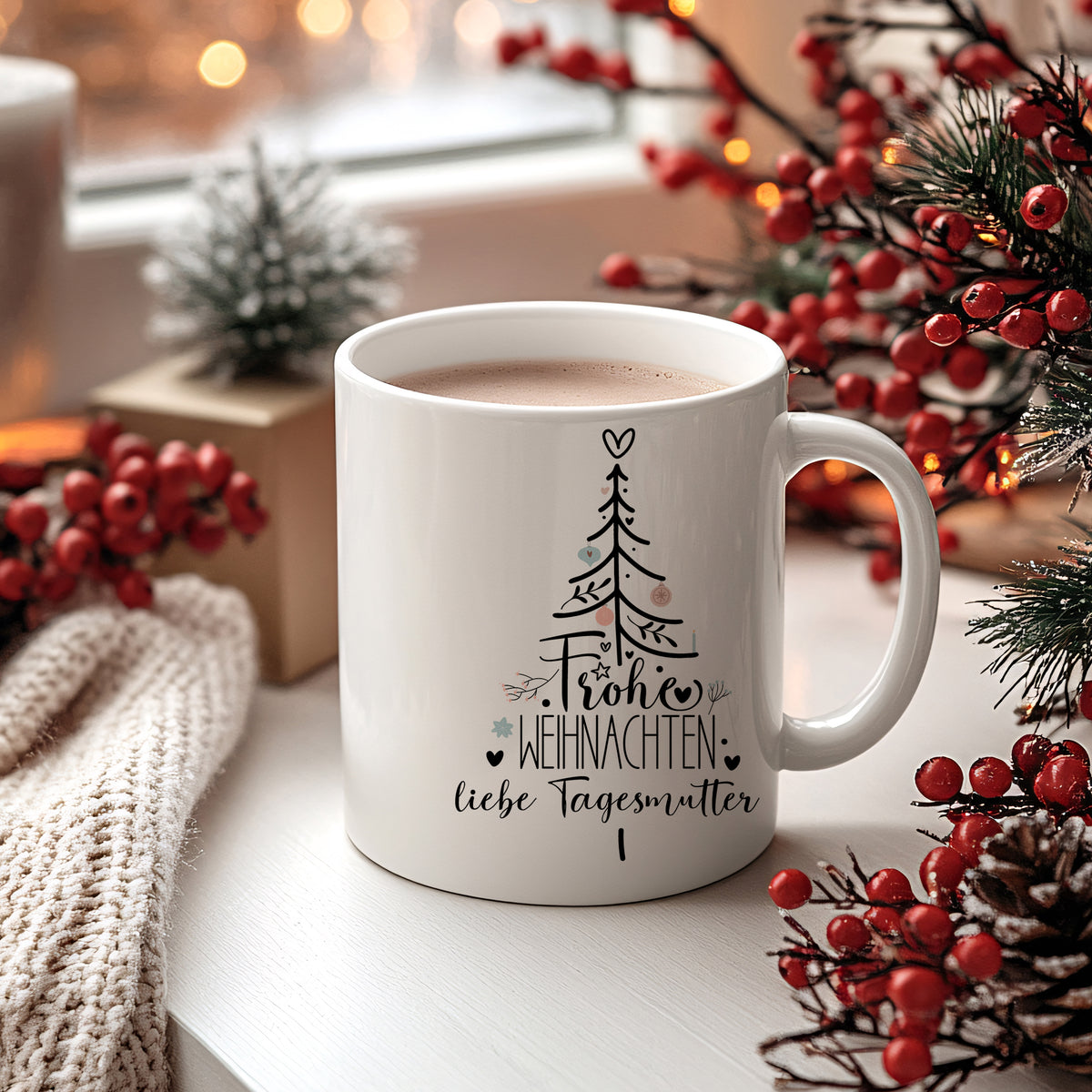 Weißer Becher mit Weihnachtsbaum und Schriftzug „Fröhliche Weihnachten“.