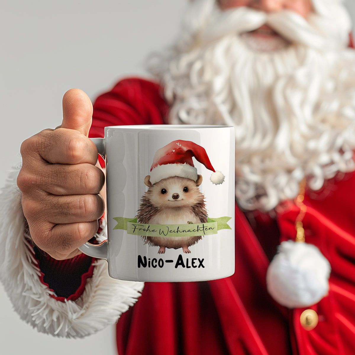 Weißer Becher mit Igel-Motiv und Weihnachtsmütze.