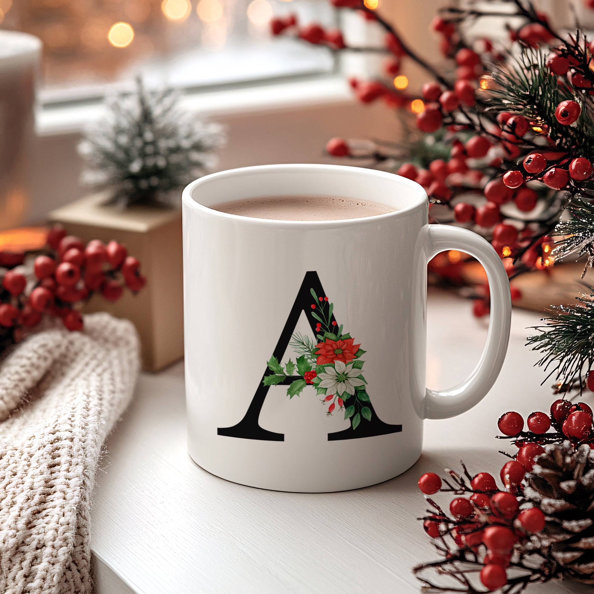 Weißer Becher mit schwarzem "A" und winterlicher Dekoration.