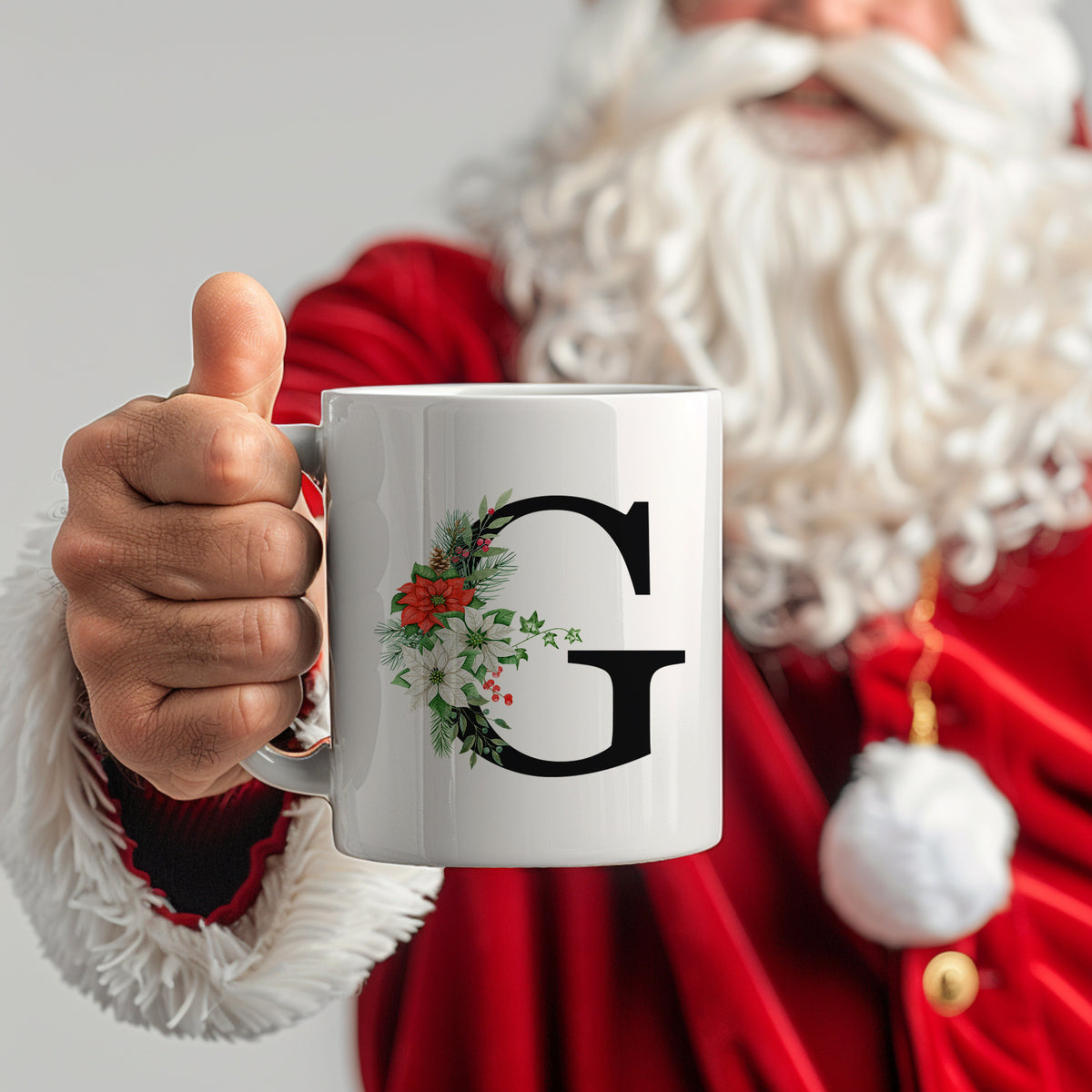 Weißer Becher mit schwarzem "G" und Weihnachtsdekoration.