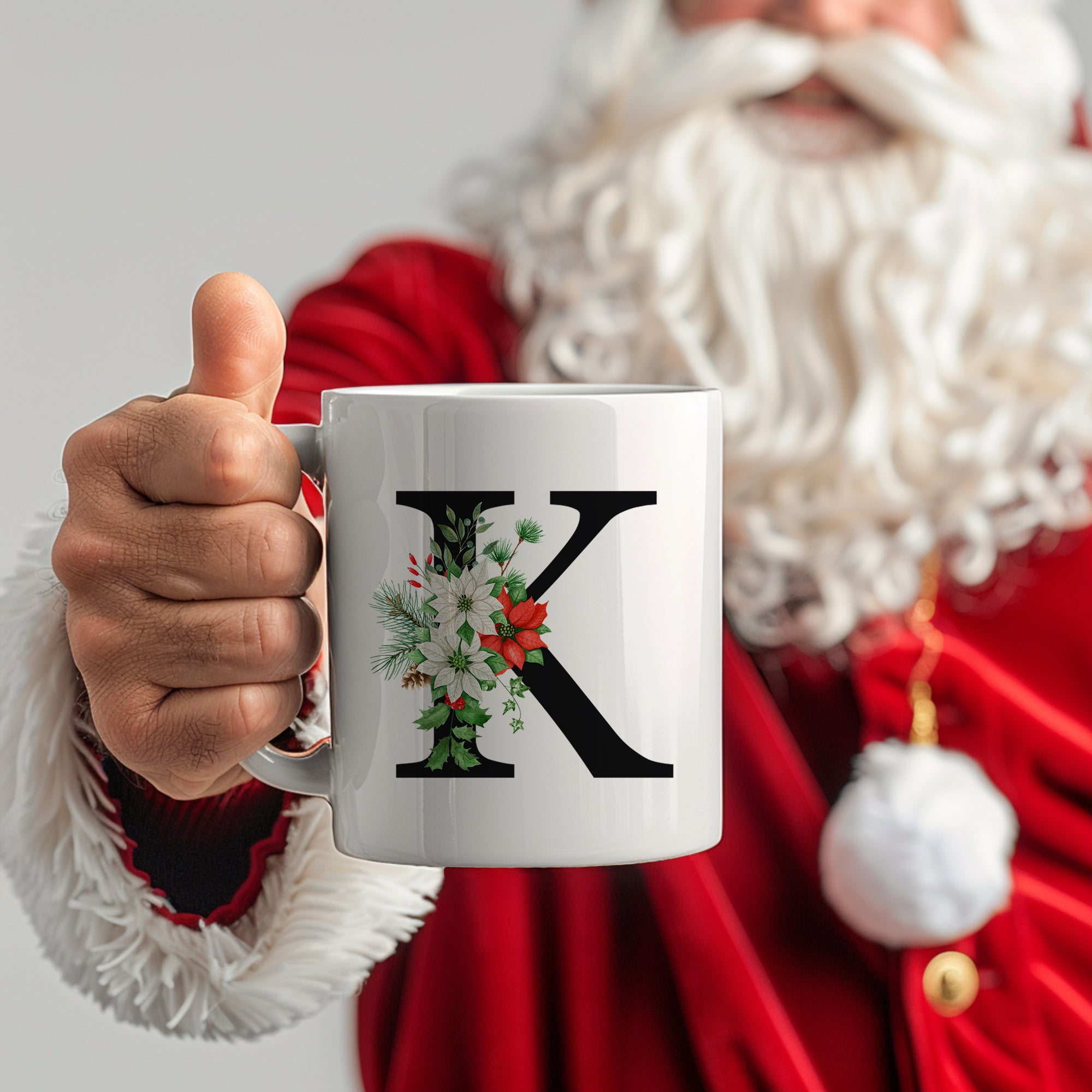 Weiße Tasse mit Buchstaben K und Weihnachtsmotiven.