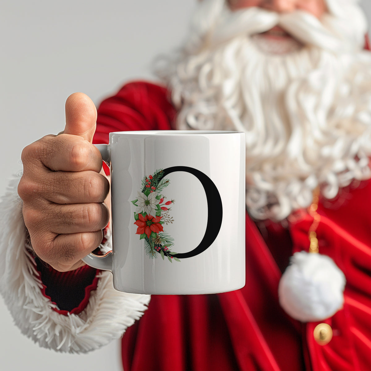 Weißer Becher mit schwarzem Buchstaben O und Weihnachtsdekor.