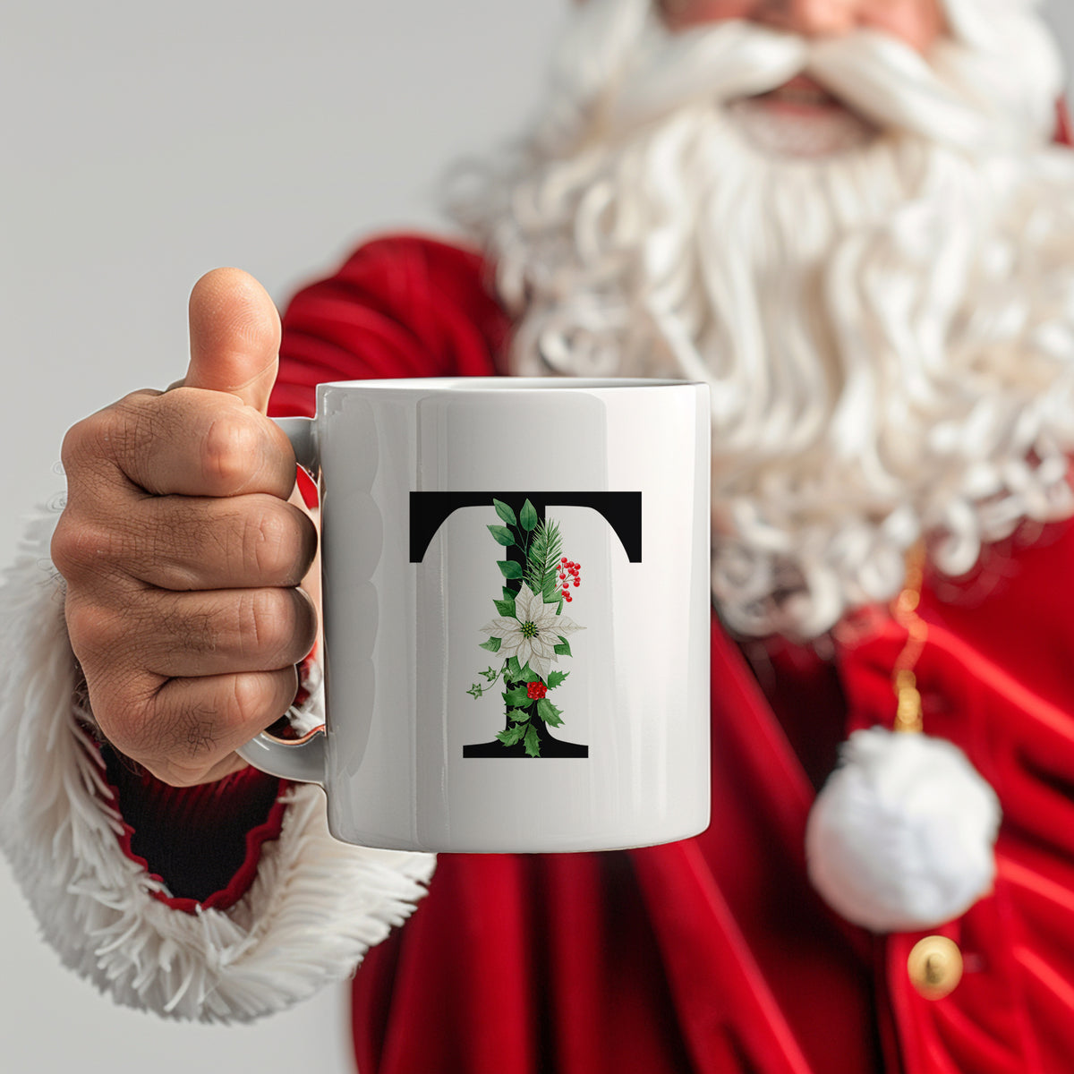 Weißer Becher mit floralem Buchstaben "T" und Weihnachtsmotiven.