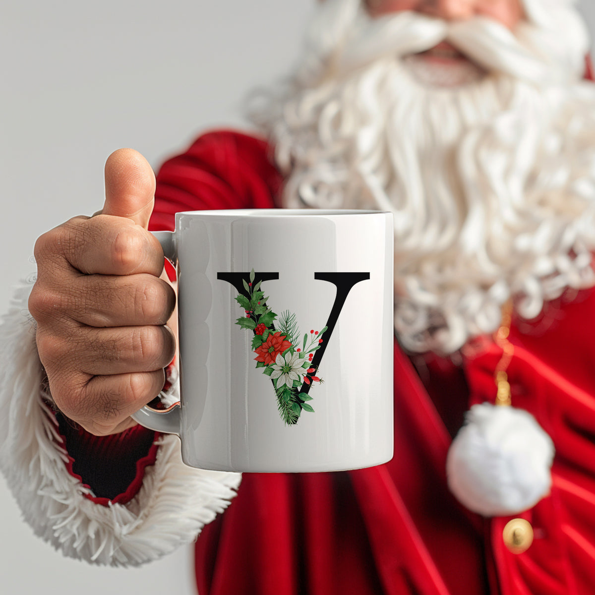 Weißer Becher mit floralem "V" und Weihnachtsmotiven.