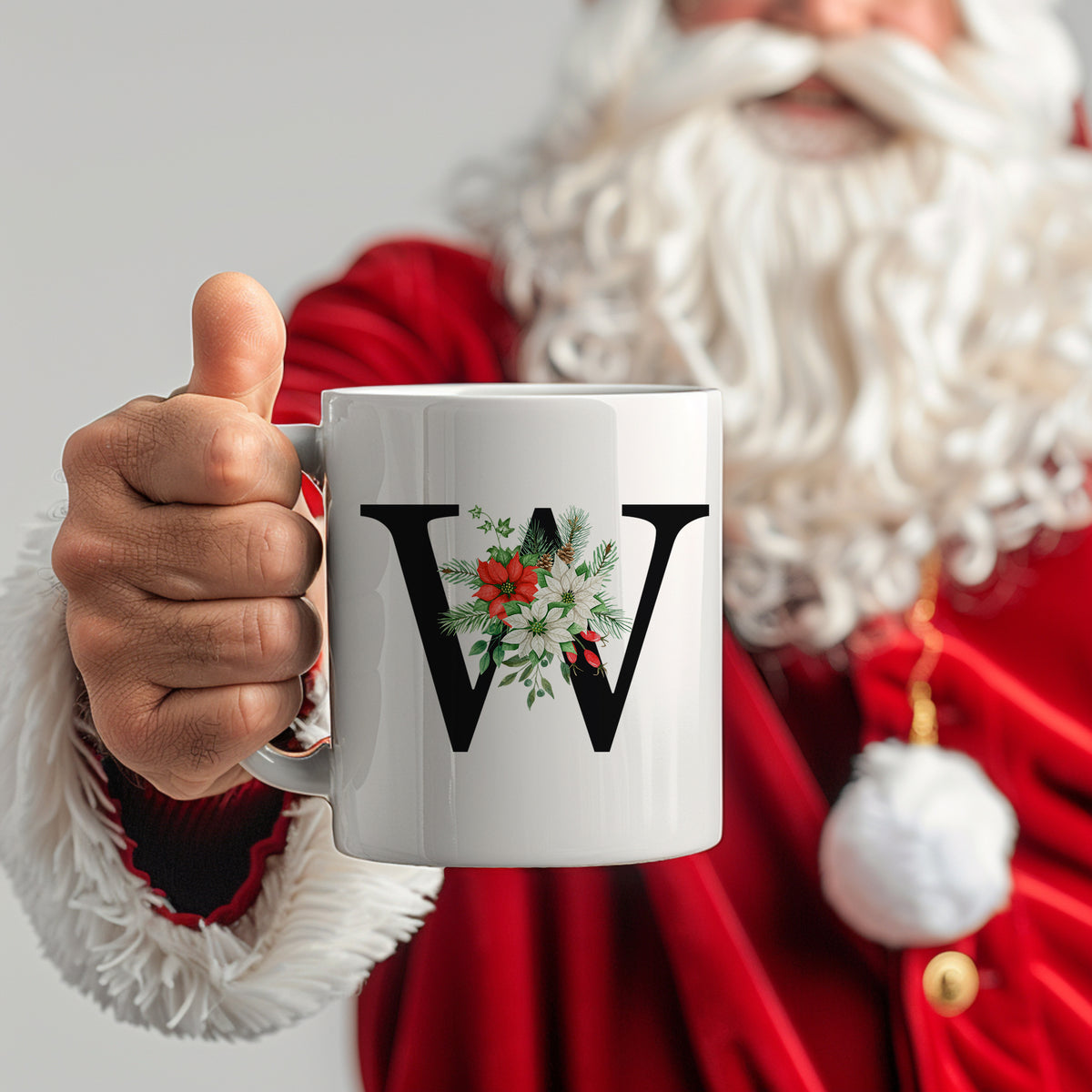 Weißer Becher mit schwarzem "W" und Weihnachtsdekor.