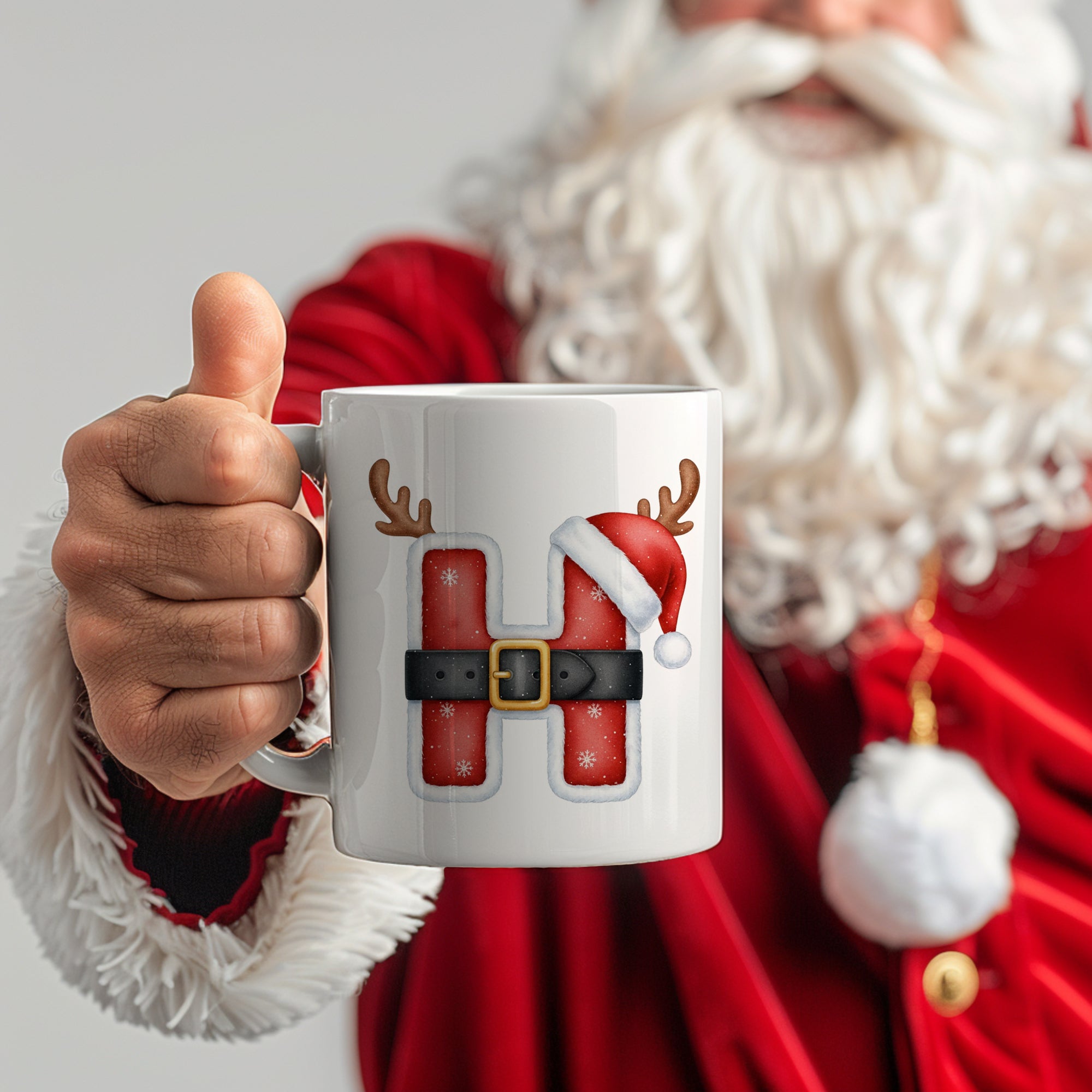 Weißer Becher mit rotem Weihnachtsmann-Design und Buchstaben "H".