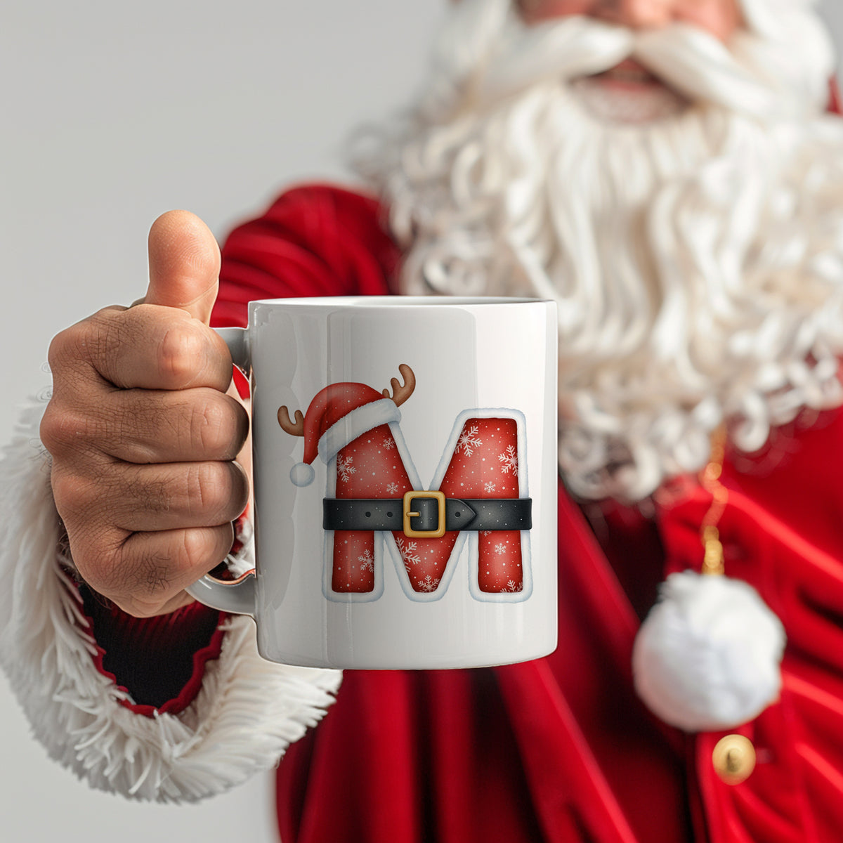 Weißer Becher mit rotem "M" und Weihnachtsmotiv.