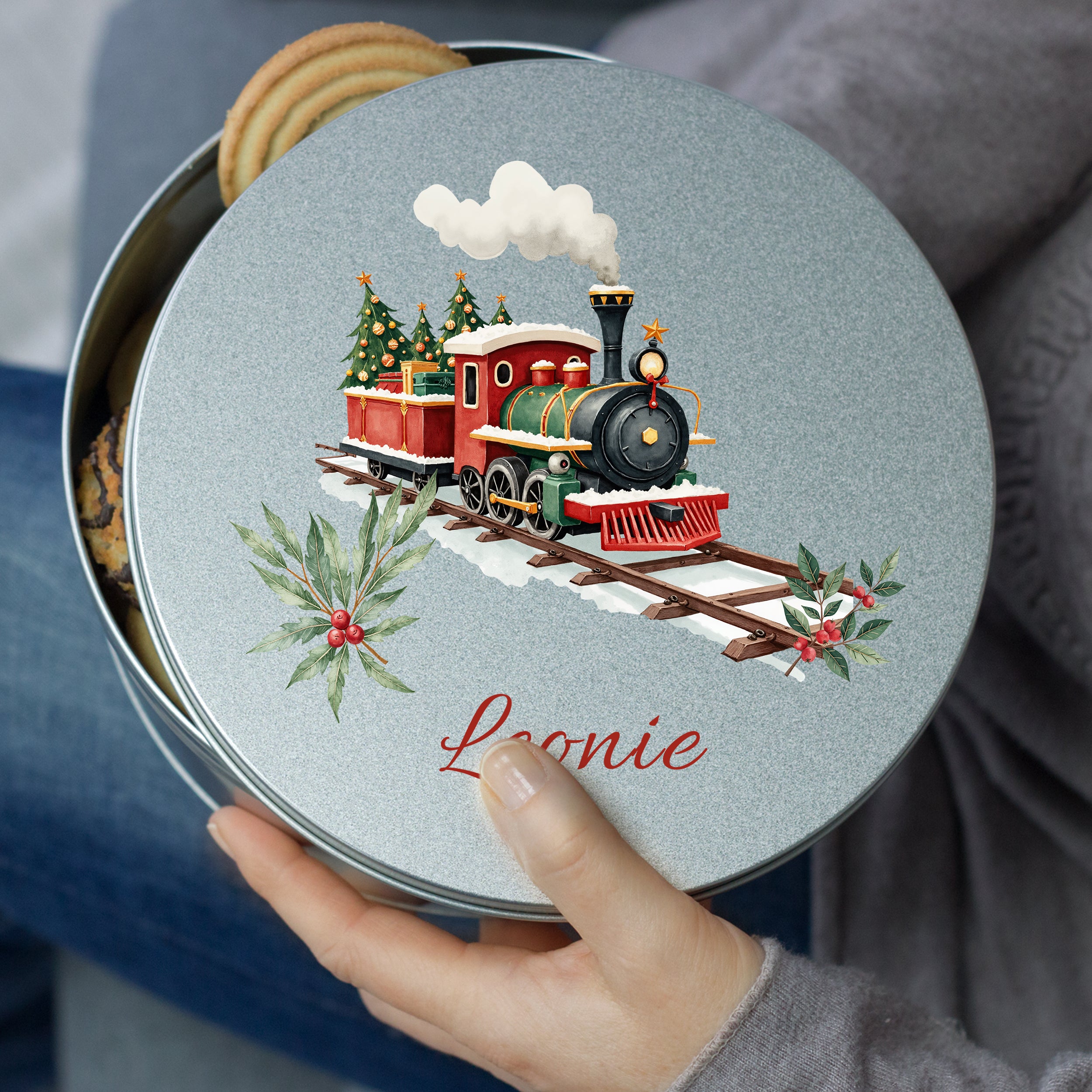 Runde Keksdose mit rotem Zug und Weihnachtsbaum-Motiv.