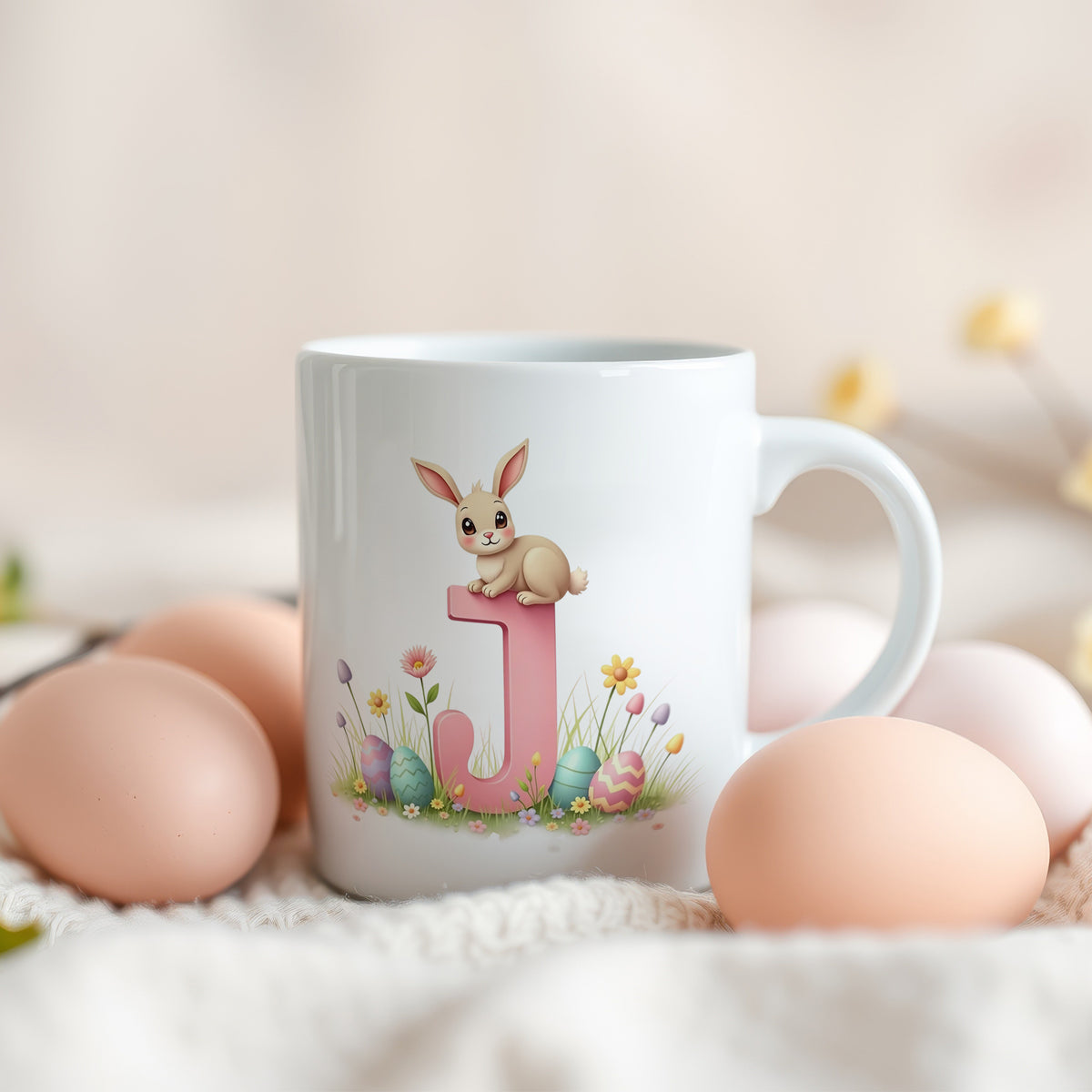 Weißer Becher mit rosa Buchstaben J und Hasenmotiv.