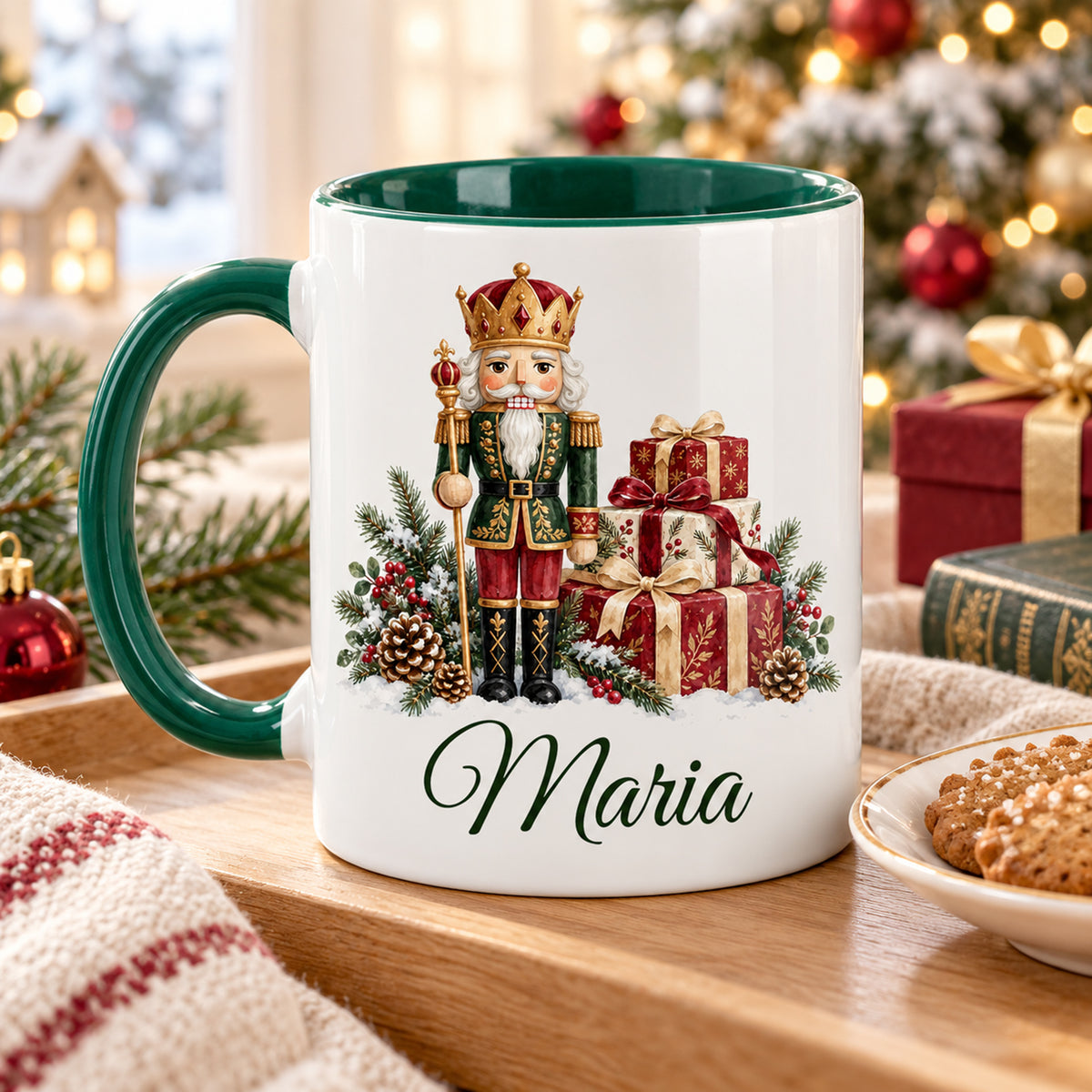Weiße Keramiktasse mit grünem Henkel und grüner Innenseite, Motiv König mit Geschenken und Wunschname auf einem Tablett mit Gebäck in weihnachtlicher Umgebung.