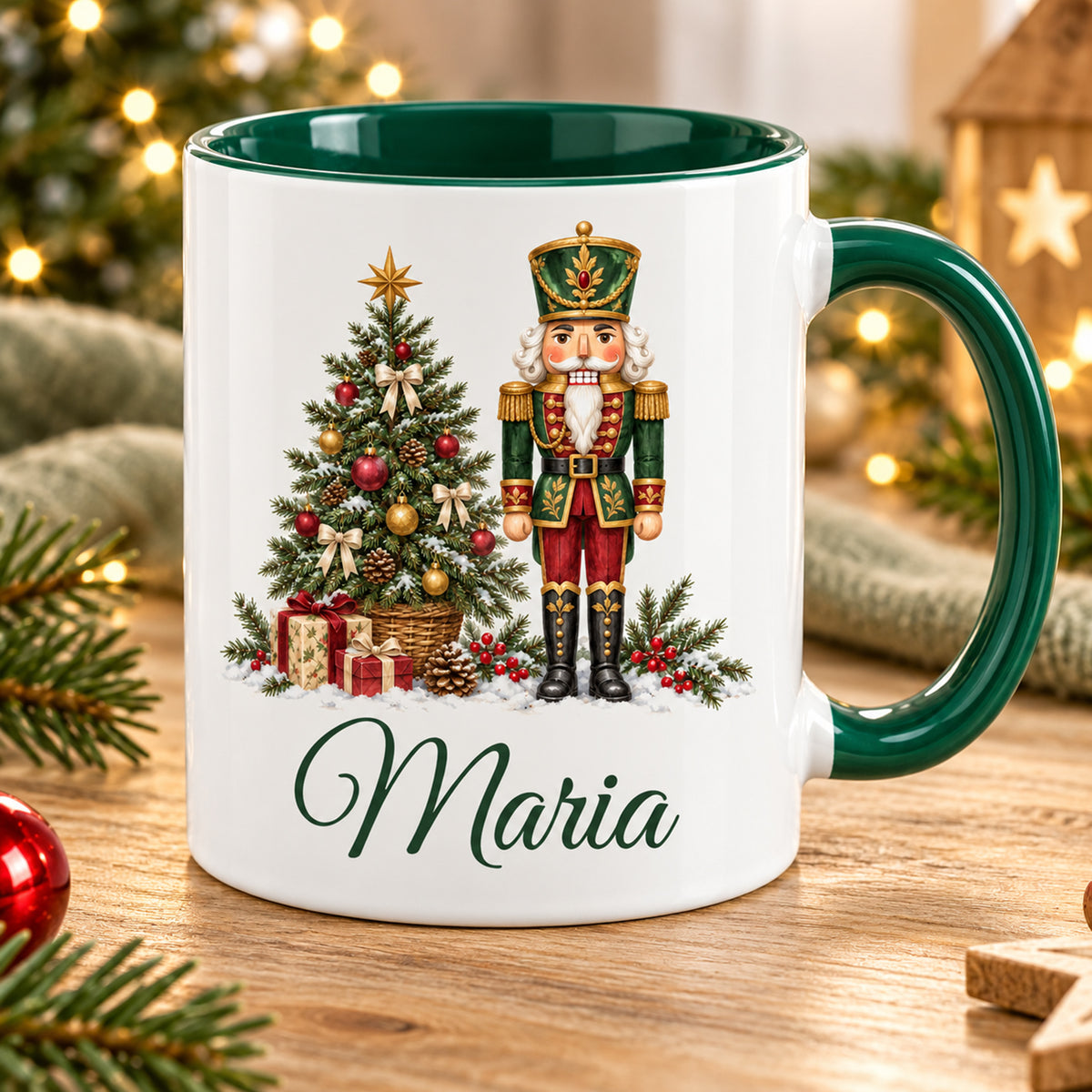 Weiße Keramiktasse mit grünem Henkel und grüner Innenseite, Motiv Tannenbaumwächter und Wunschname vor weihnachtlicher Dekoration.
