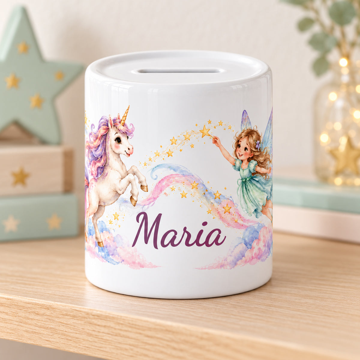 Personalisierte Spardose mit Fee, Einhorn und Sternen auf einem hellen Möbel neben pastellfarbenen Sternen und Geschenkboxen.