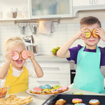 Bunte Kekse, Kinder mit bunten Schürzen, fröhliche Stimmung.
