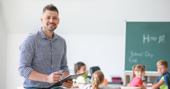 Lehrer mit Klemmbrett in einem Klassenzimmer.
