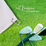 Helle Tasche mit Karabiner und Golfschlägern auf Rasen.