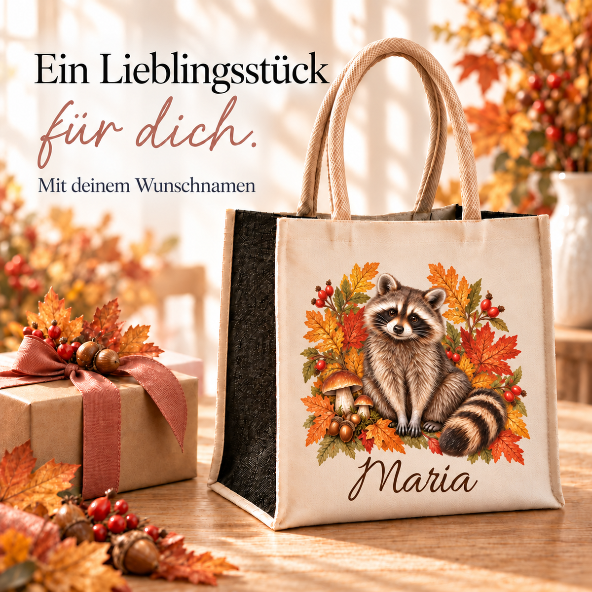 Einkaufstasche mit herbstlichem Waschbär-Motiv und Wunschname neben einem verpackten Geschenk.