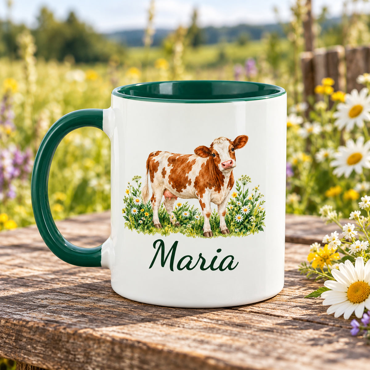 Kuh-Tasse mit braun-weißer Kuh zwischen Wildblumen und Wunschname mit Henkel links, gegenüberliegende Druckseite im Grünen