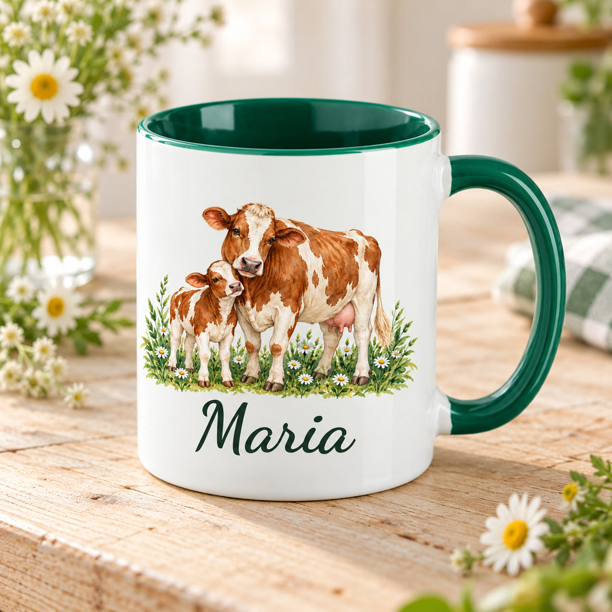 Kuh-Tasse mit braun-weißer Kuh und Kälbchen zwischen Wiesenblumen und Wunschname in Schrägansicht mit sichtbarem dunkelgrünem Innenraum