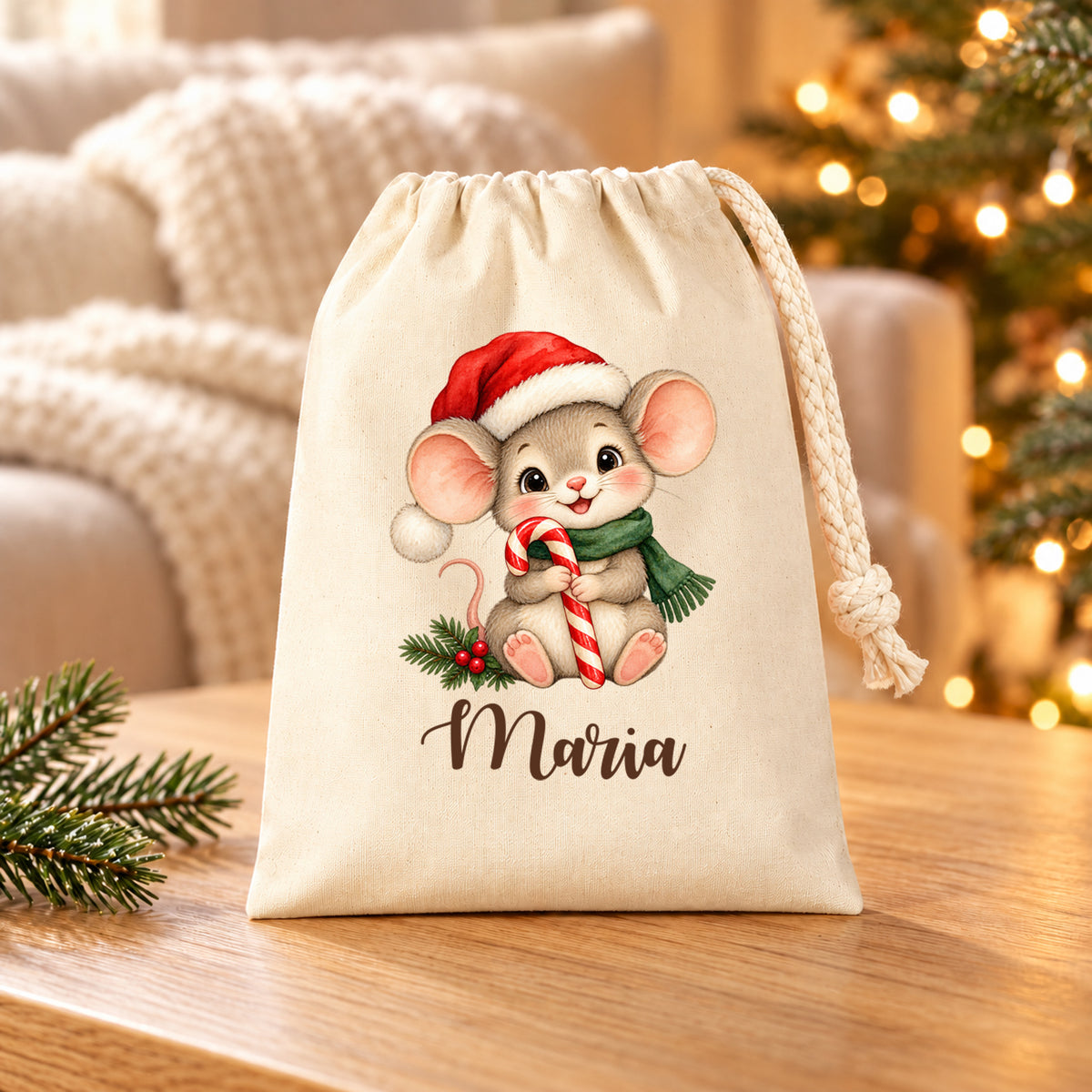 Naturfarbenes Nikolaussäckchen mit Weihnachtsmaus mit Zuckerstange und personalisiertem Namen auf einem Holztisch vor Sofa und Weihnachtslichtern.